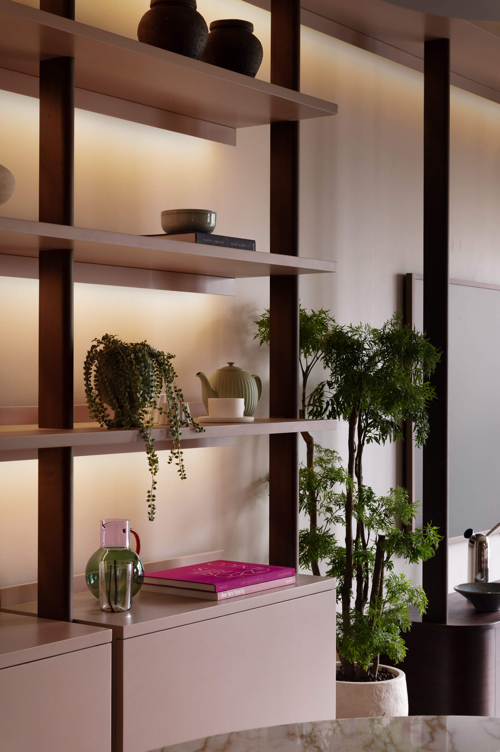 In the dining area, a custom bookshelf and soft lighting create a warm, layered atmosphere that connects seamlessly with the living space.
