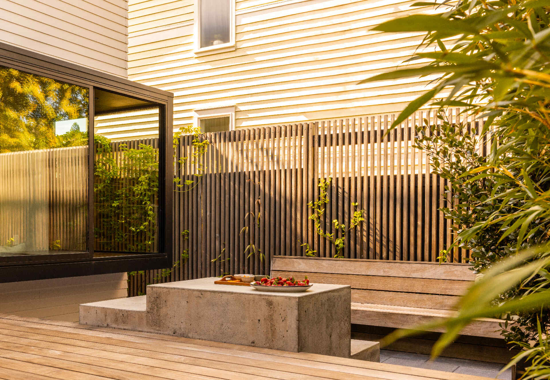 A compact backyard transforms into a layered outdoor retreat with a firepit, built-in seating, and a playful corner window connection.