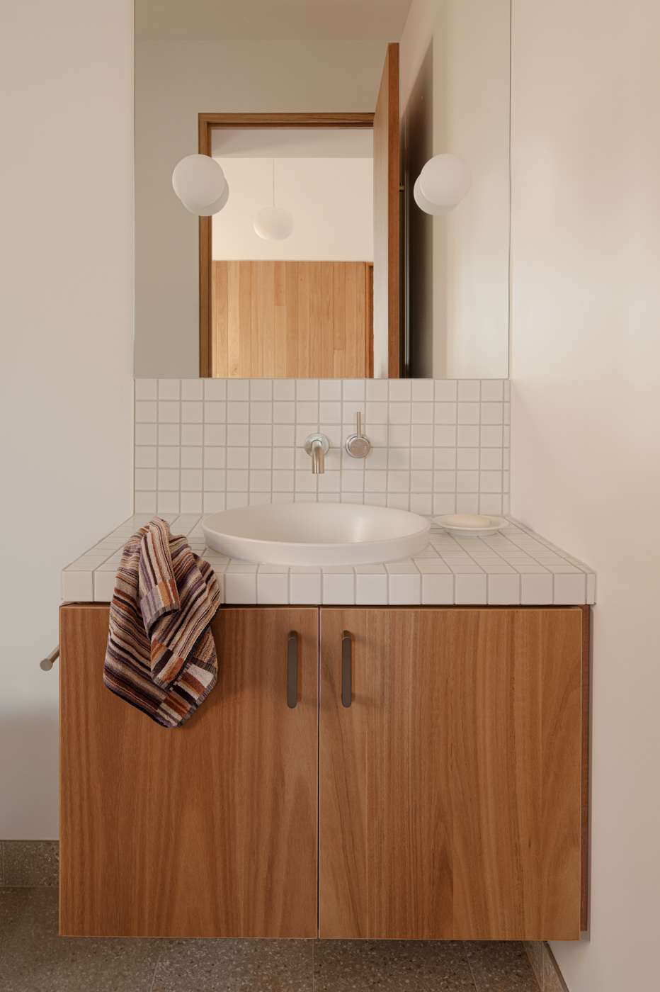 A modern bathroom with white tiles and a floating wood vanity.