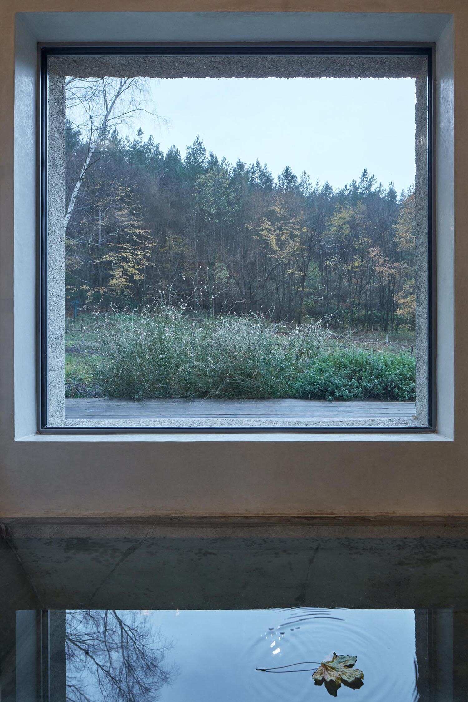 A bathroom with a sunken tub and large picture window, bringing natural light and forest views inside.