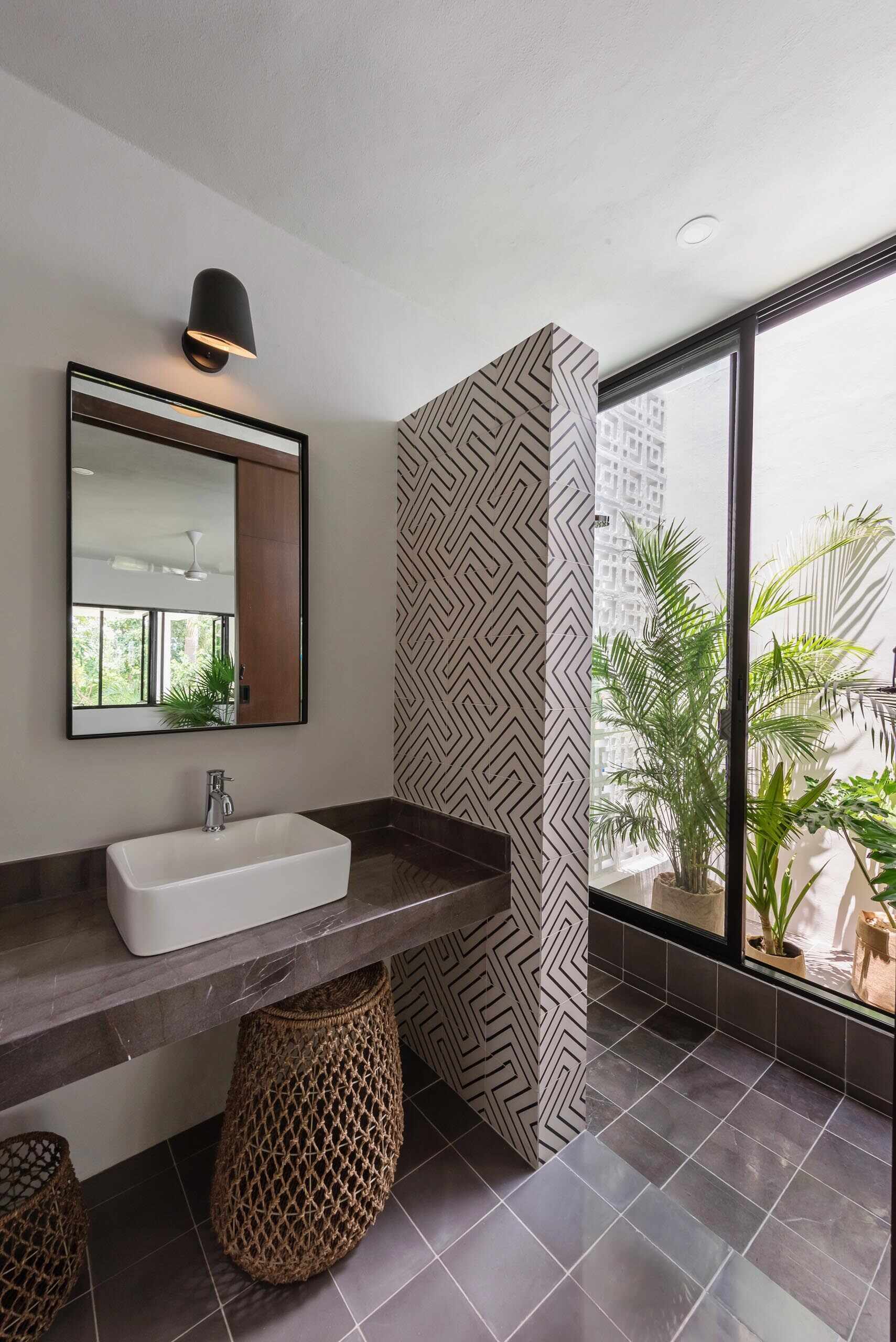 Graphic patterned tiles reappear in the bathroom, where they form a striking divider between the shower and vanity.