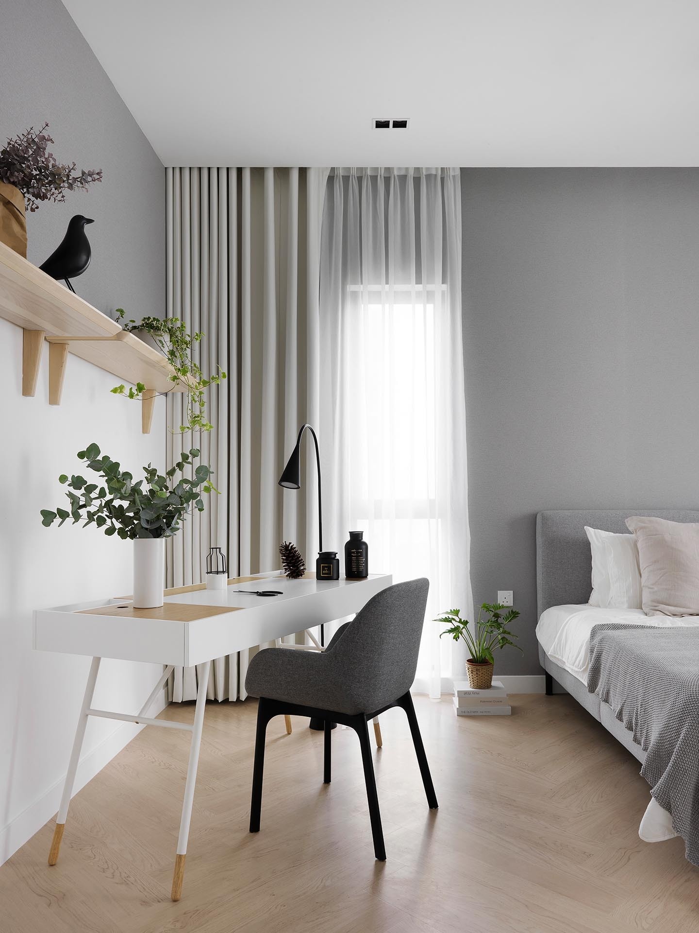 Herringbone wood flooring, neutral colors, natural fibers, and plants create a calm bedroom in this Scandinavian-inspired apartment designed by PINS Studio.