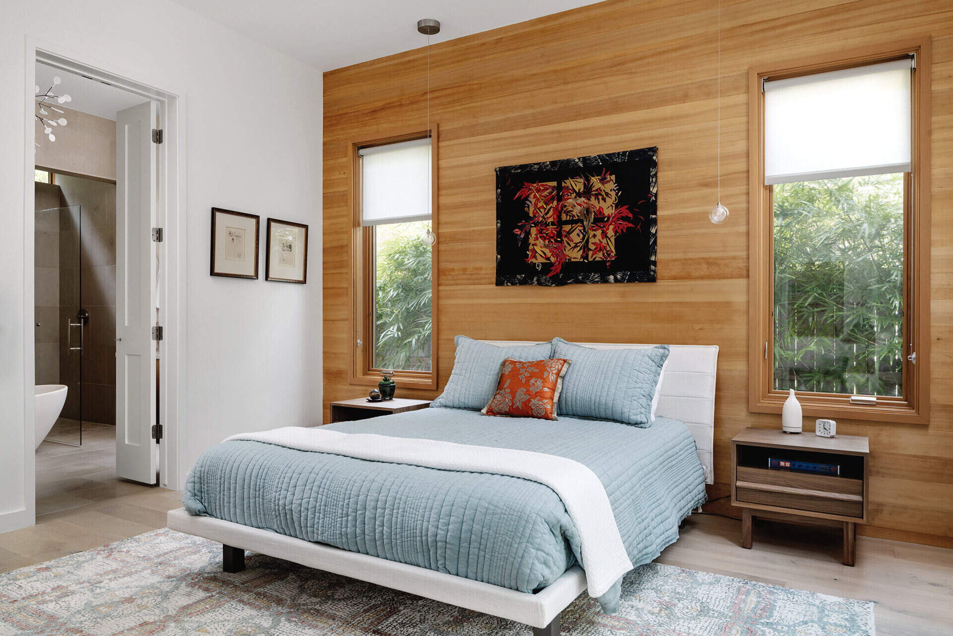 A warm wood accent wall and a door leading outdoors give this Austin bedroom a calm, grounded atmosphere that connects the private interior space with nature.