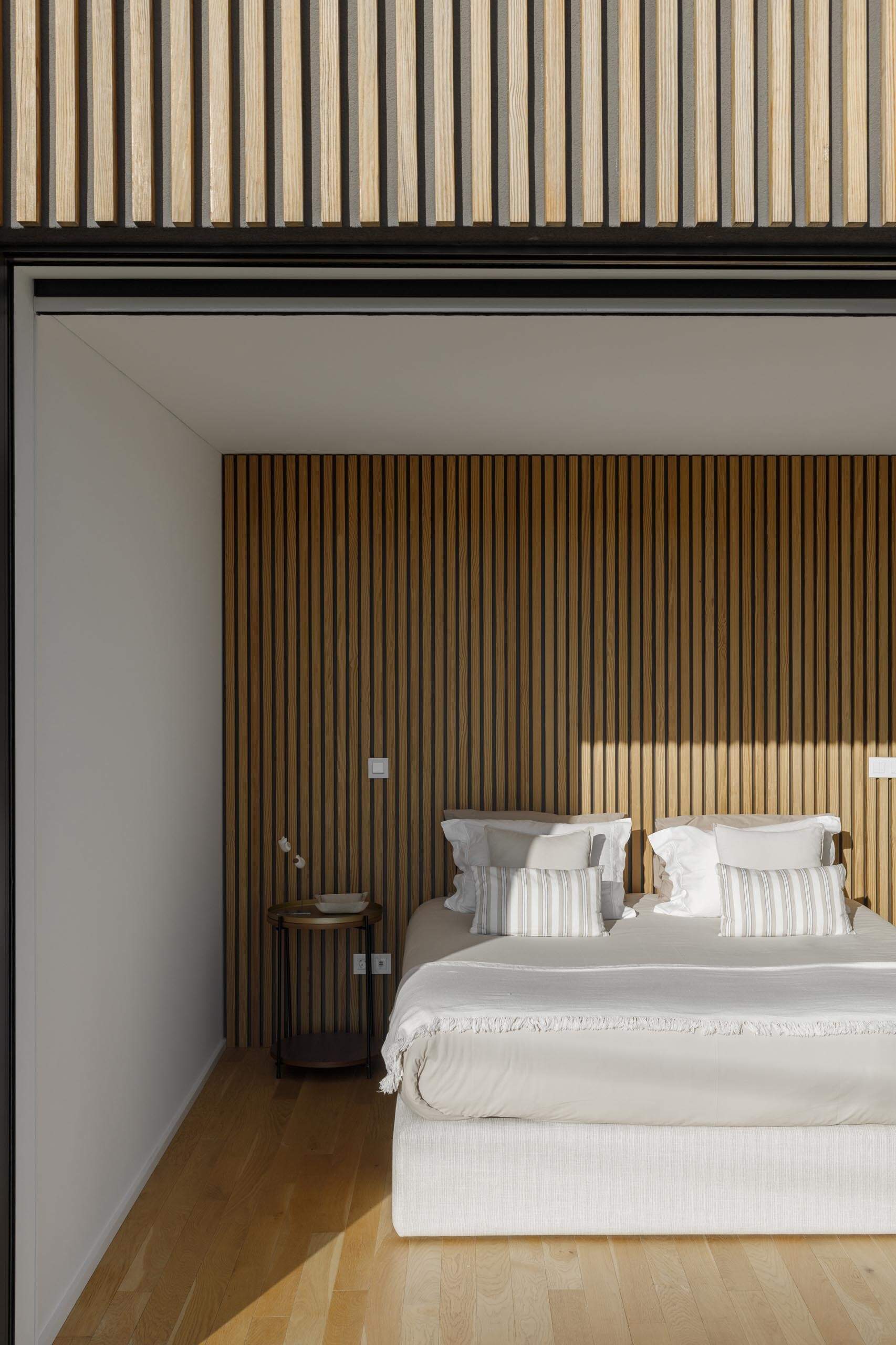 A wood slat feature wall in the bedroom reflects the exterior facade, adding warmth and texture to the interior.