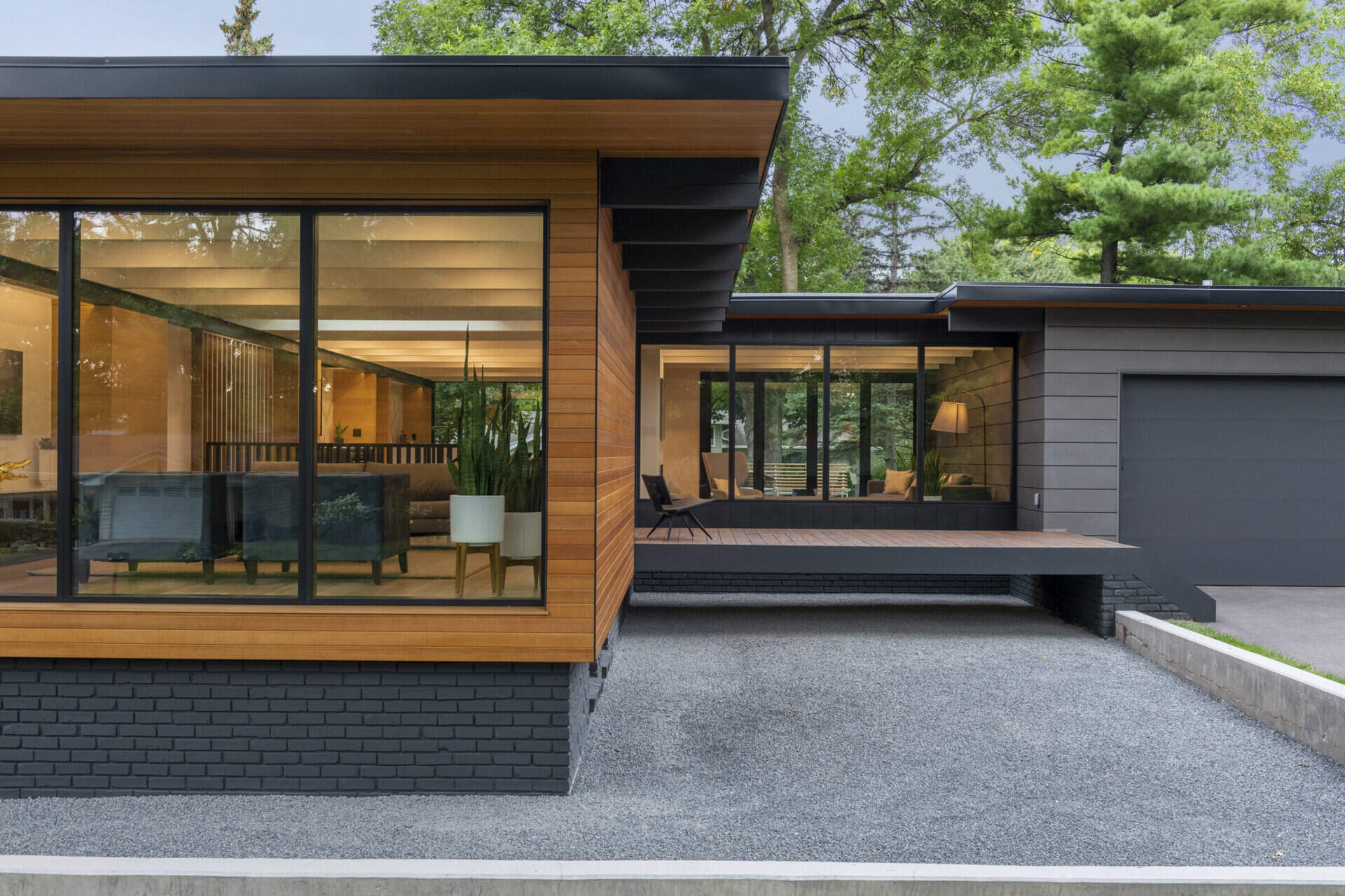 El exterior negro y de madera de esta casa de Golden Valley se destaca contra el telón de fondo de árboles maduros y un patio espacioso. Un pequeño puente conduce a la puerta principal, lo que aumenta el encanto de este diseño de mediados de siglo.