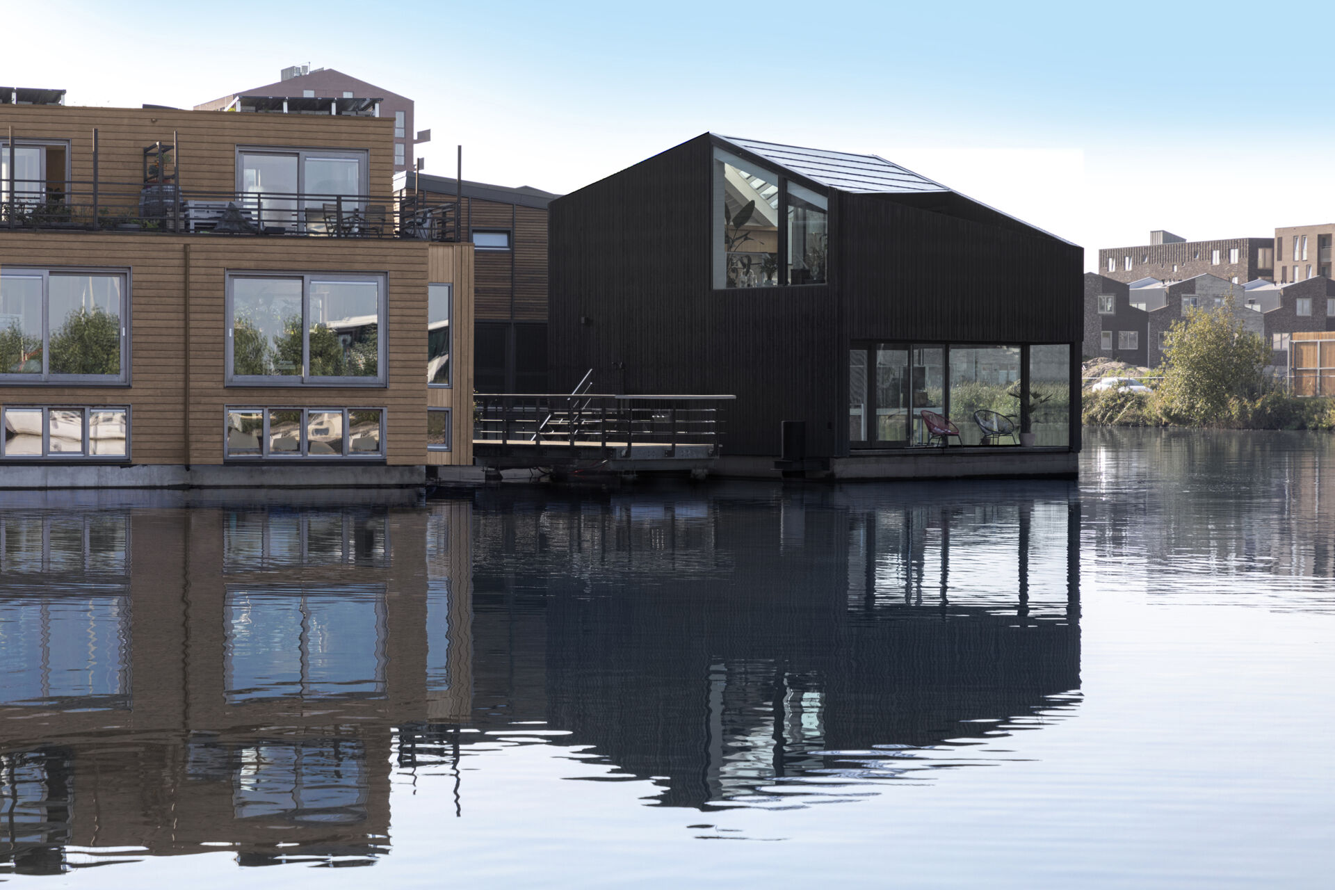 A black timber floating home in Amsterdam shows how a simple form can stand out on water while staying clean and minimal.