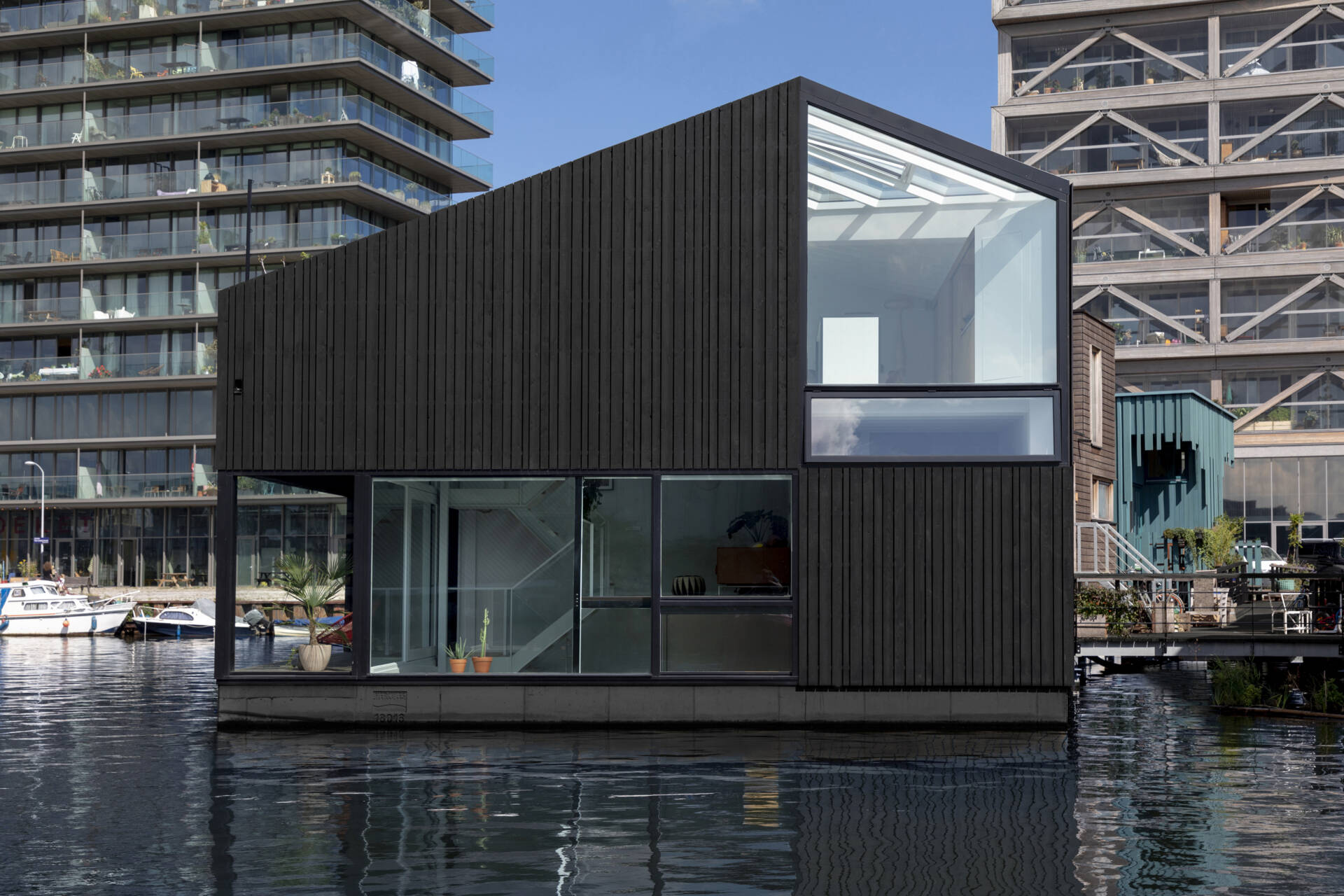 A black timber floating home in Amsterdam shows how a simple form can stand out on water while staying clean and minimal.