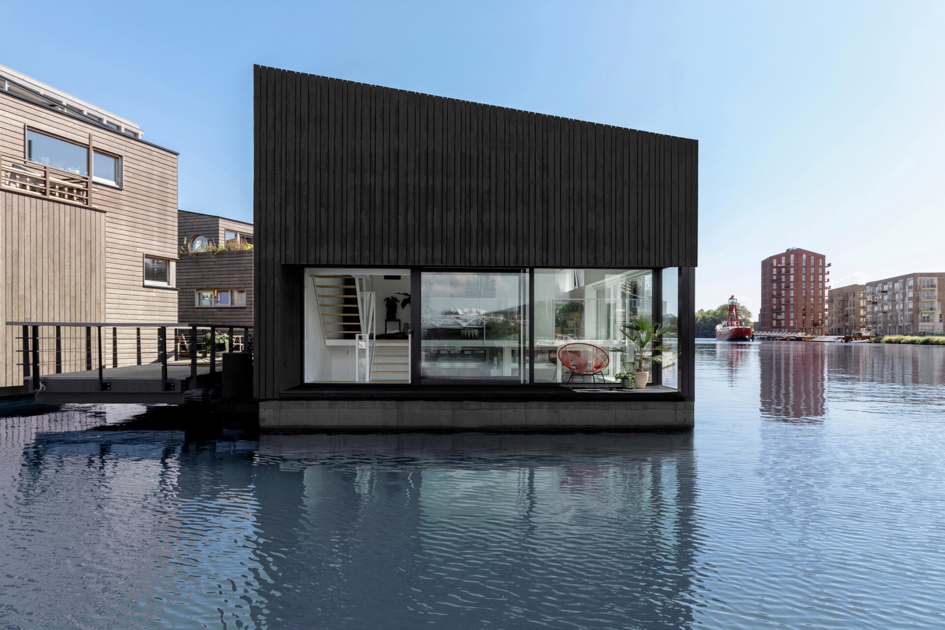 A black timber floating home in Amsterdam shows how a simple form can stand out on water while staying clean and minimal.