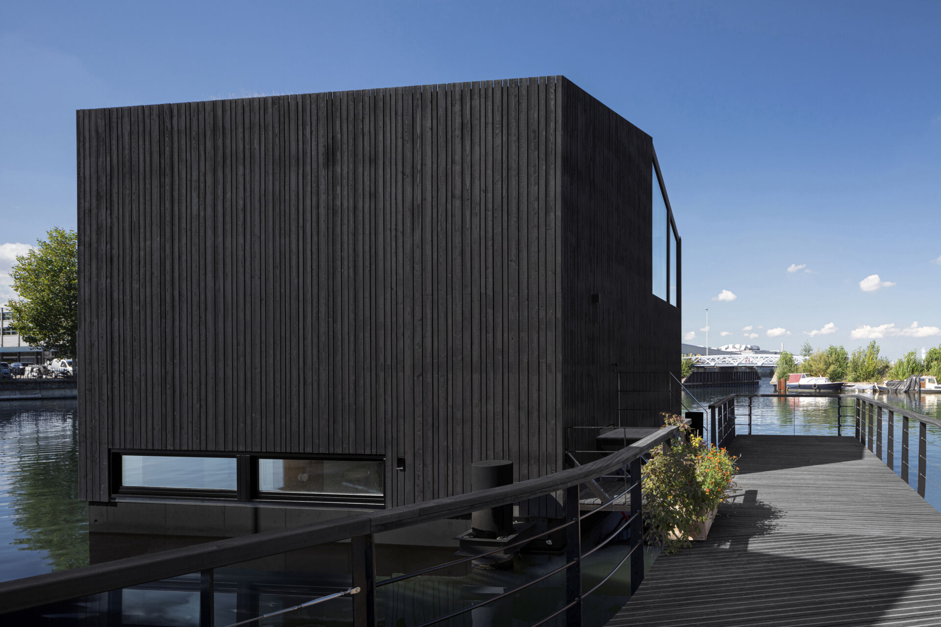 A black timber floating home in Amsterdam shows how a simple form can stand out on water while staying clean and minimal.