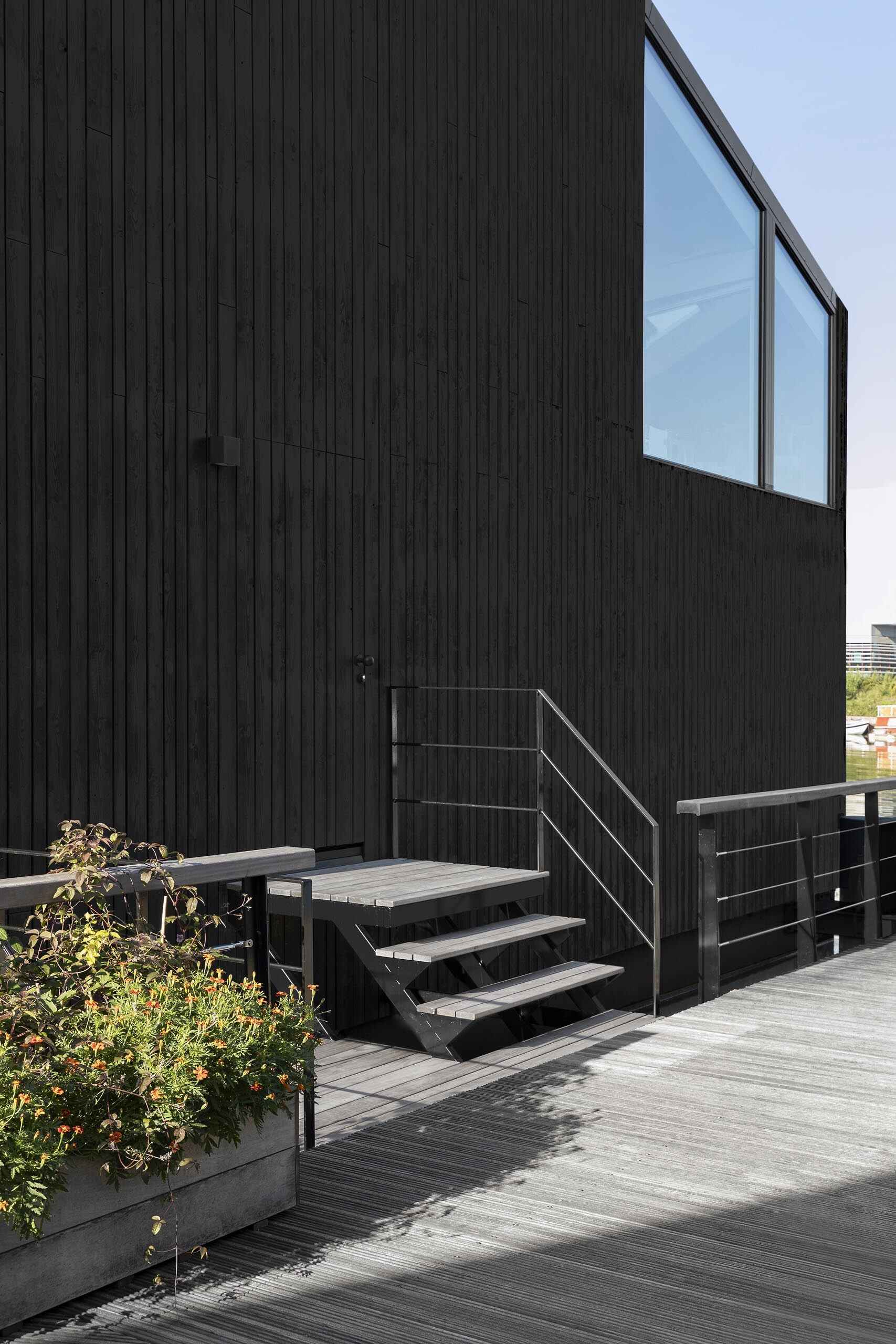 A hidden front door blends into the black wood facade, creating a seamless and understated entry.