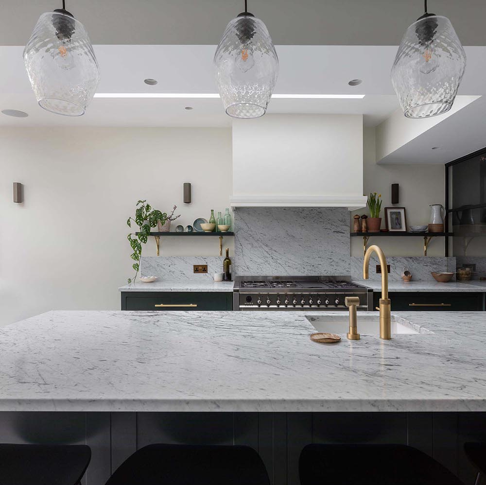 Dark kitchen cabinets paired with gray marble countertops and brass fixtures create a modern yet durable kitchen at the heart of the home.