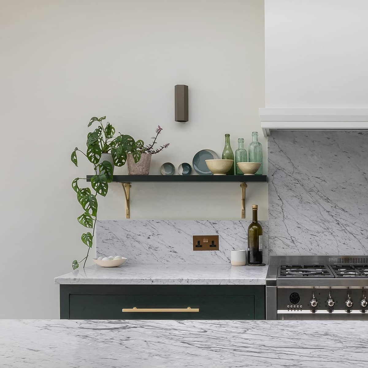 Dark kitchen cabinets paired with gray marble countertops and brass fixtures create a modern yet durable kitchen at the heart of the home.