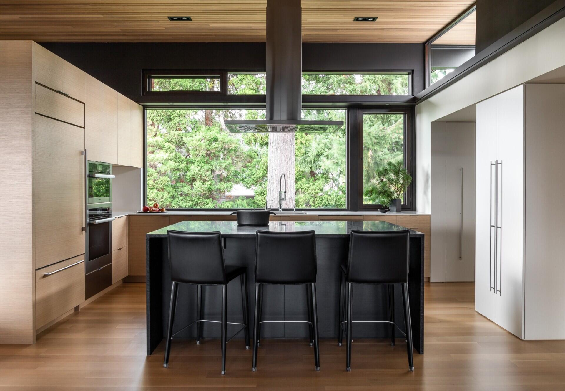 A modern kitchen with a black island and a mix of white and wood cabinetry for a clean, balanced look.