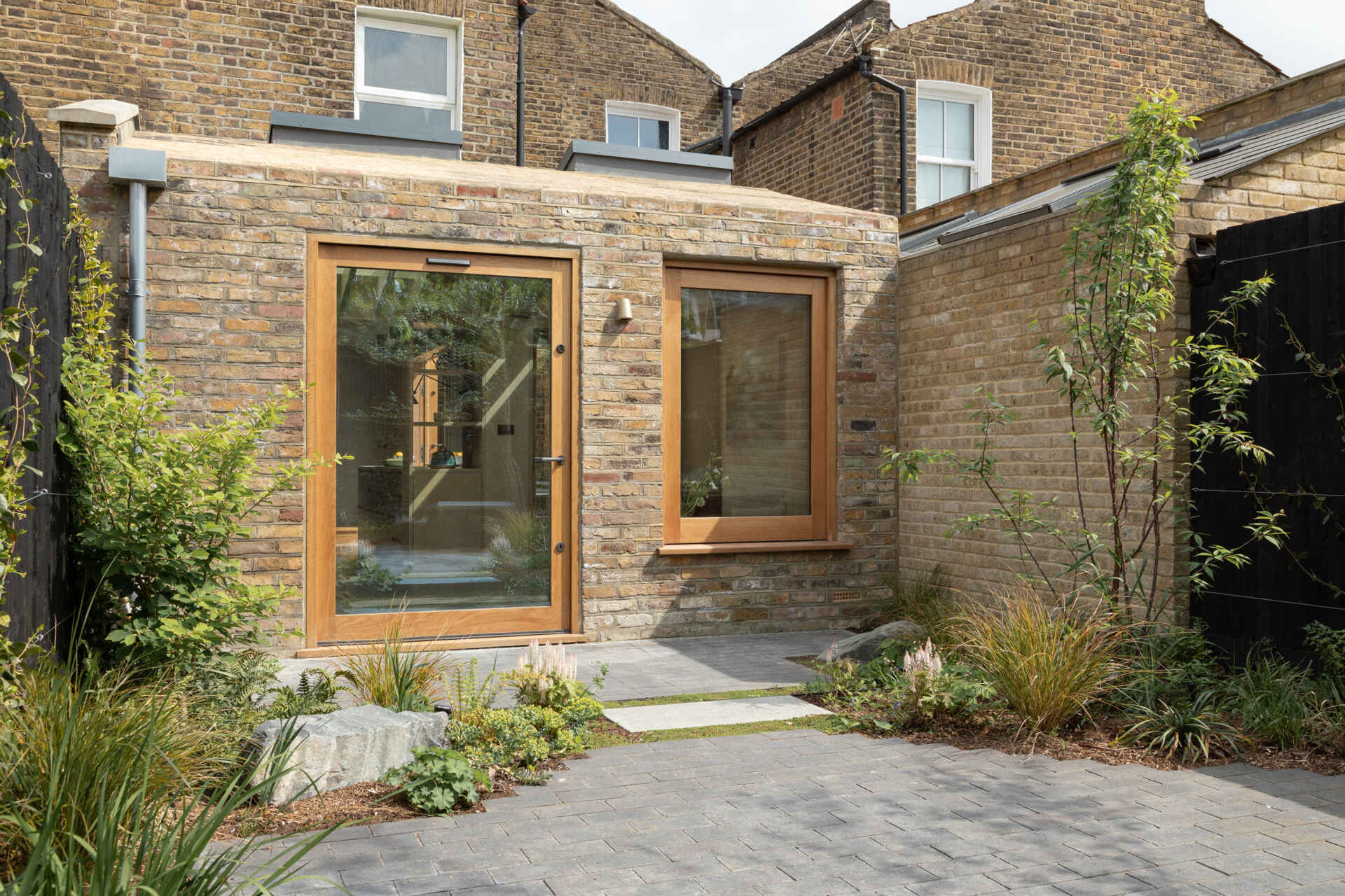 Una extensión inspirada en una cabaña de Turner Architects transforma el borde de un pequeño jardín urbano en un espacio de salón y cocina sólido y basado en materiales.