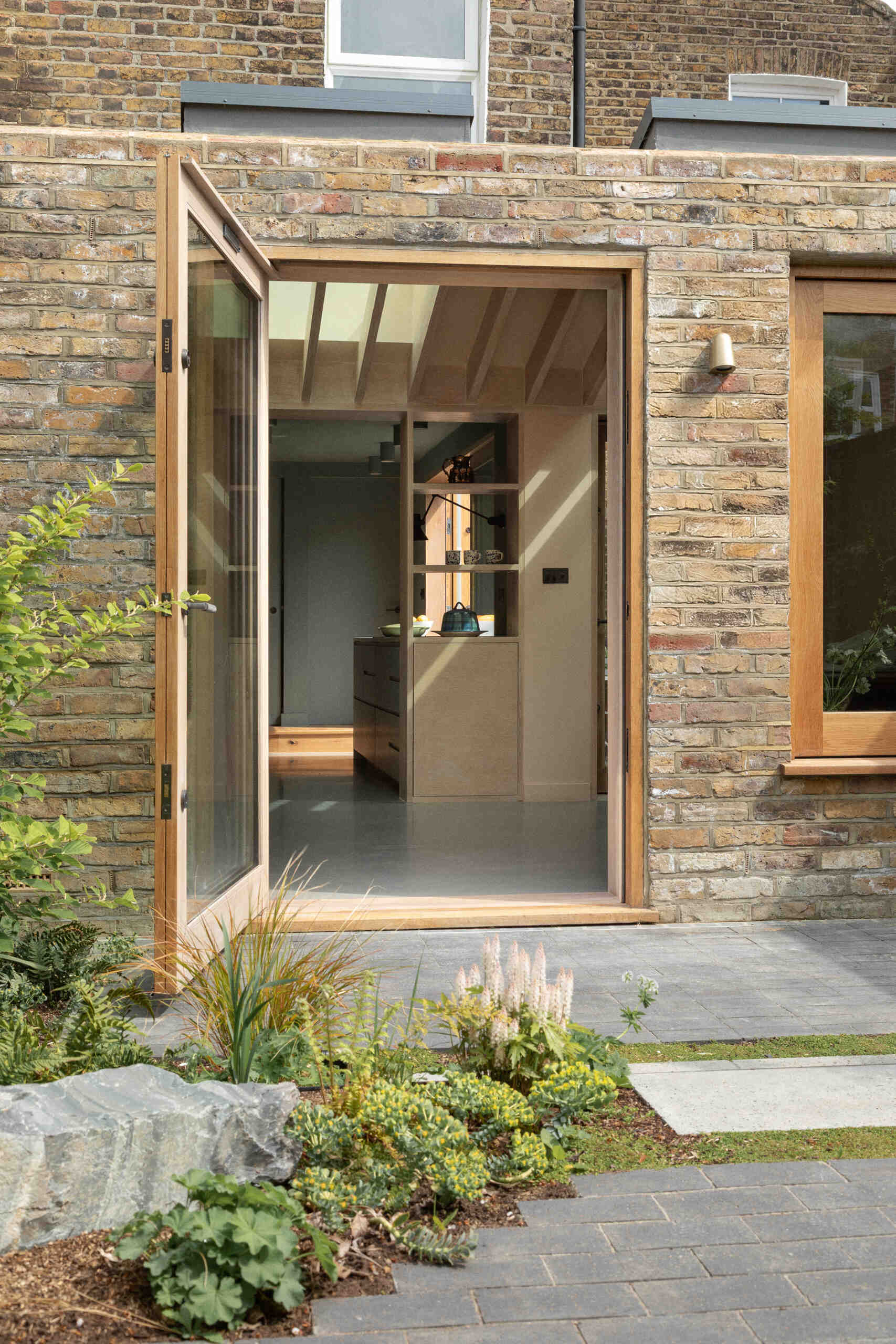 Una extensión inspirada en una cabaña de Turner Architects transforma el borde de un pequeño jardín urbano en un espacio de salón y cocina sólido y basado en materiales.