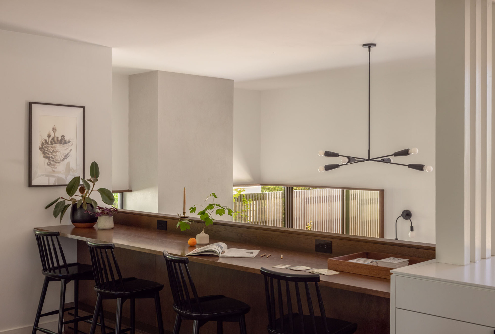 A built-in oak workbench and bookshelf create a functional transition point between the original house and the new addition.