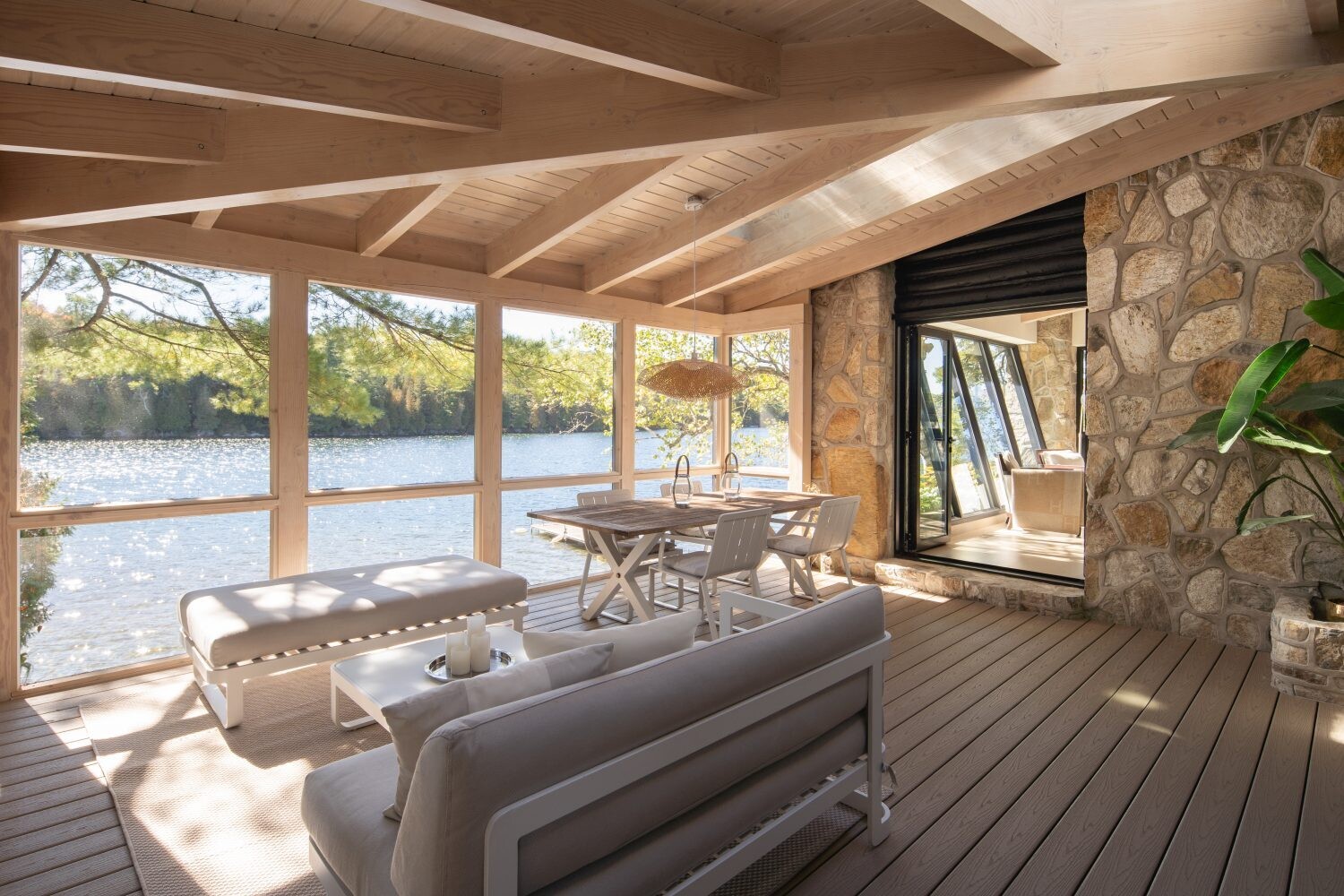 The screened porch extends the living space outdoors with a dining table, sofa, and bench, offering a relaxed place to enjoy lake breezes and filtered sunlight.