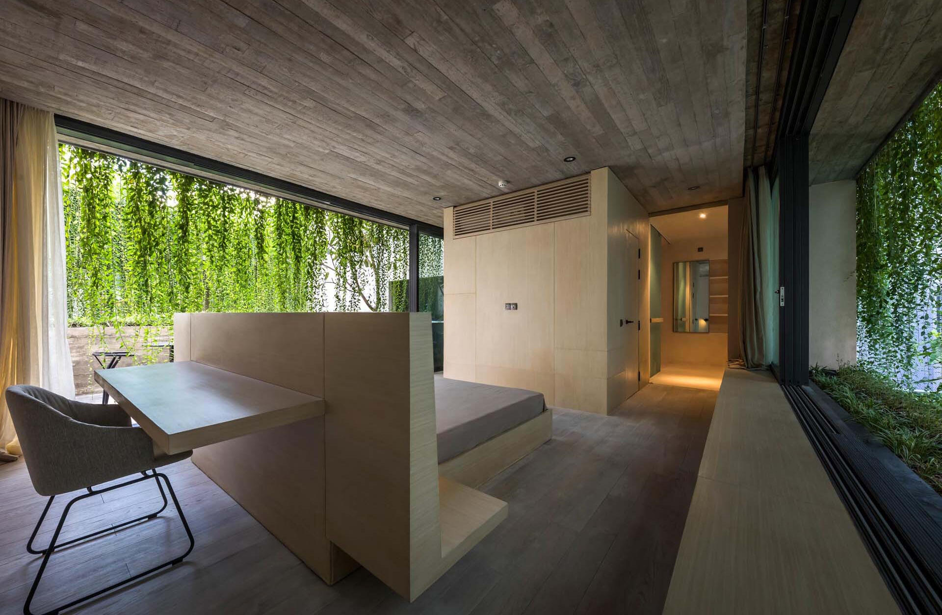 Una estructura de cama personalizada con un escritorio incorporado detrás de la cabecera convierte un dormitorio en un espacio funcional y eficiente sin agregar muebles adicionales.