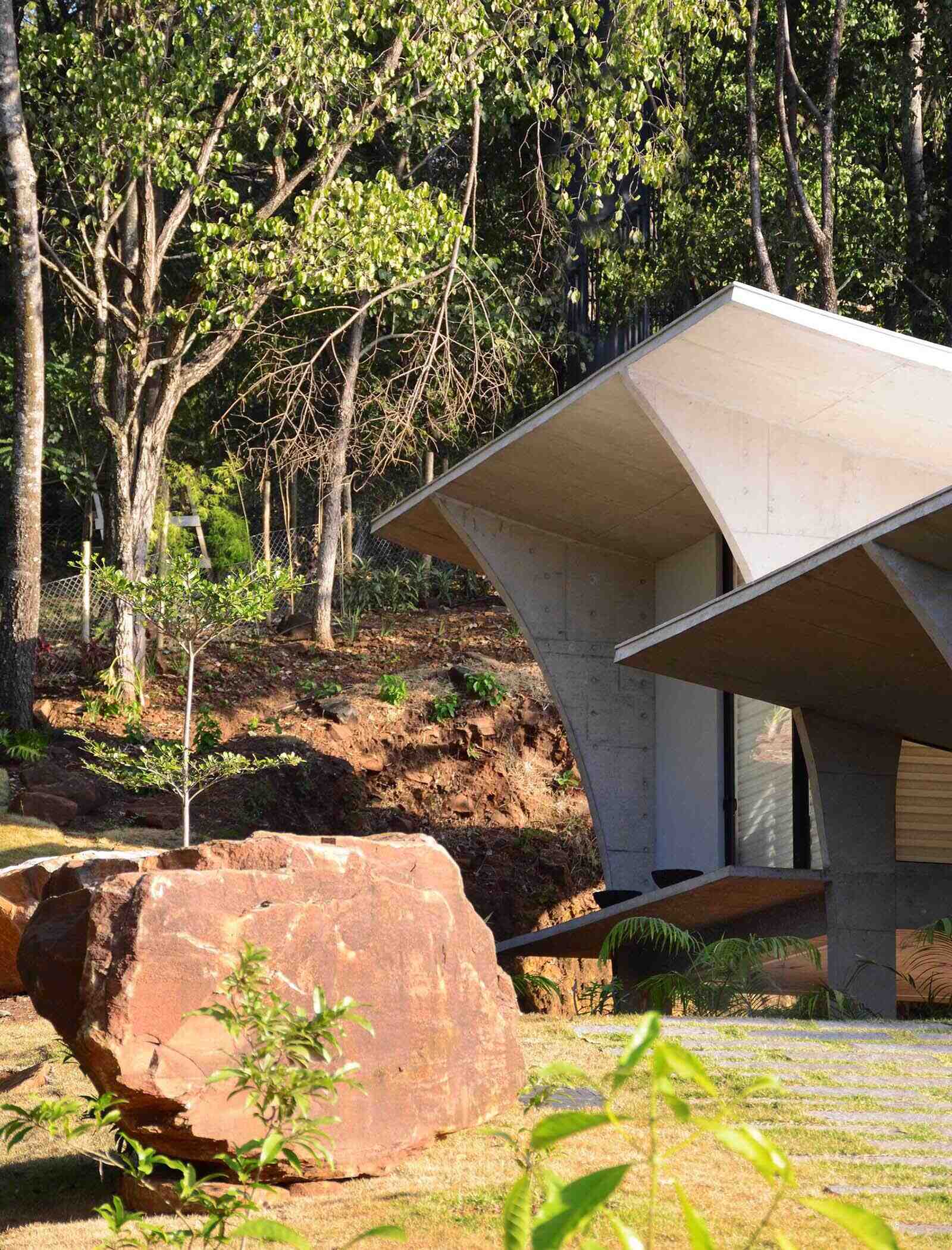 A winding concrete ramp leads up to Casa Joy in Brazil, revealing a sculptural modern home defined by six dramatic concrete arches and a concave roof overlooking the valley.