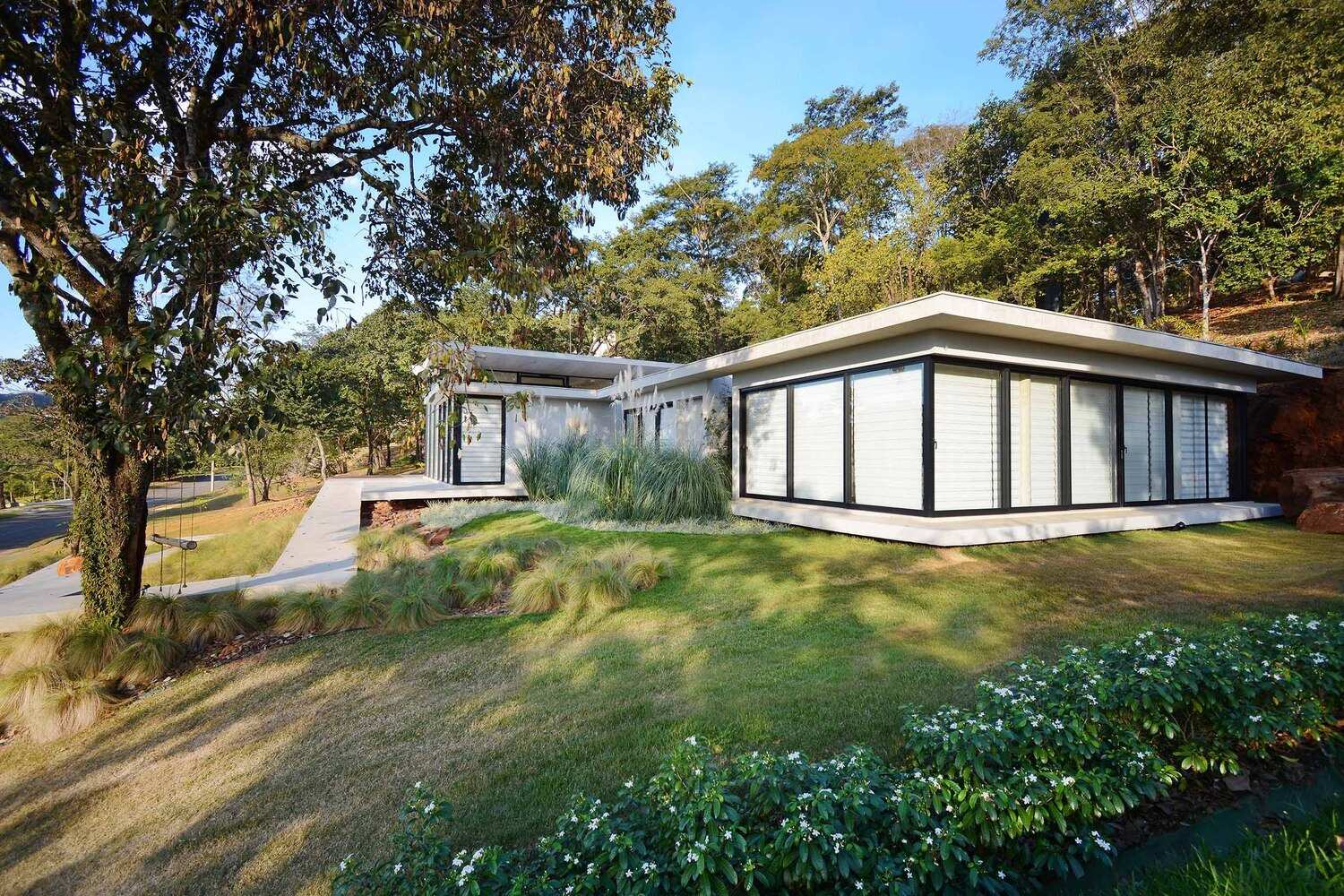 A winding concrete ramp leads up to Casa Joy in Brazil, revealing a sculptural modern home defined by six dramatic concrete arches and a concave roof overlooking the valley.