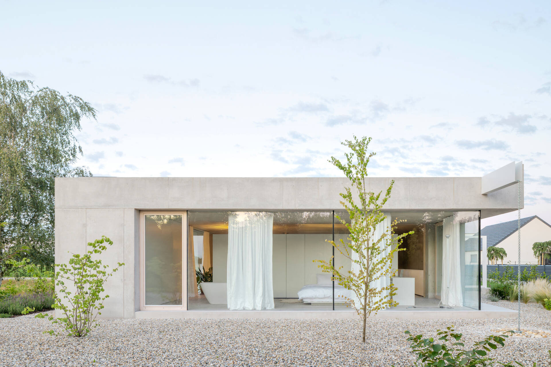 Low and horizontal, this small one bedroom concrete house uses three structural cores and a sliding glass wall to open the entire living space directly to the garden.