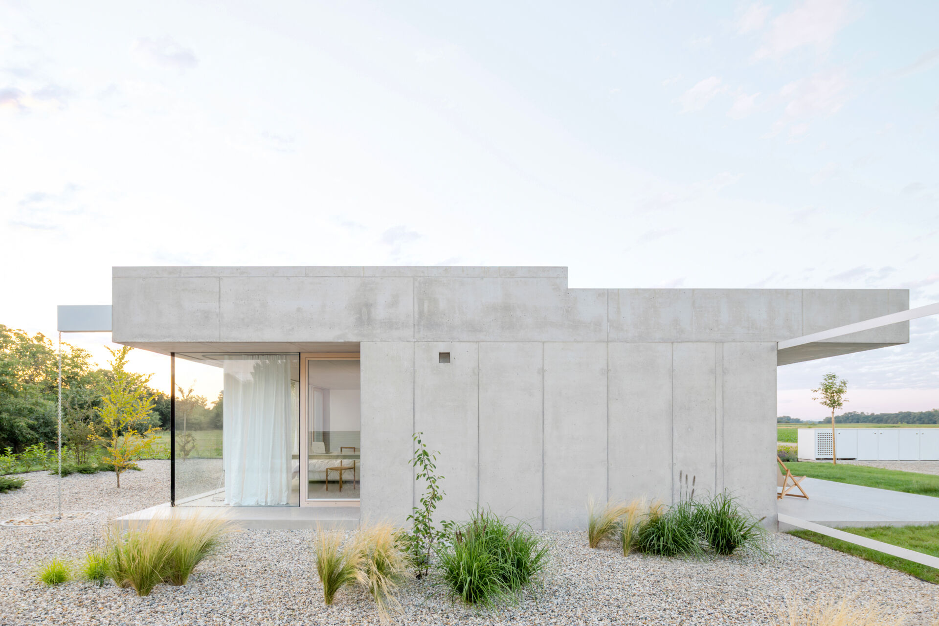 Low and horizontal, this small one bedroom concrete house uses three structural cores and a sliding glass wall to open the entire living space directly to the garden.