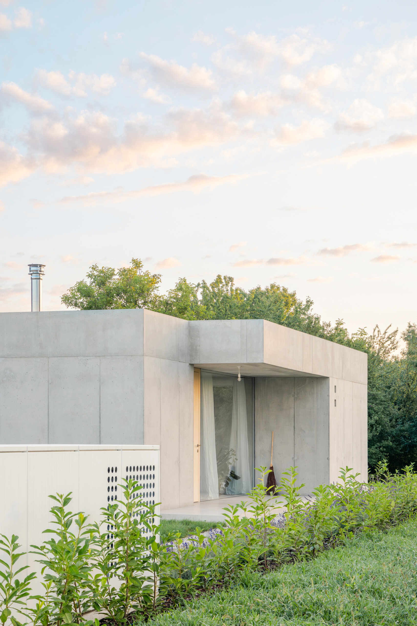 Low and horizontal, this small one bedroom concrete house uses three structural cores and a sliding glass wall to open the entire living space directly to the garden.