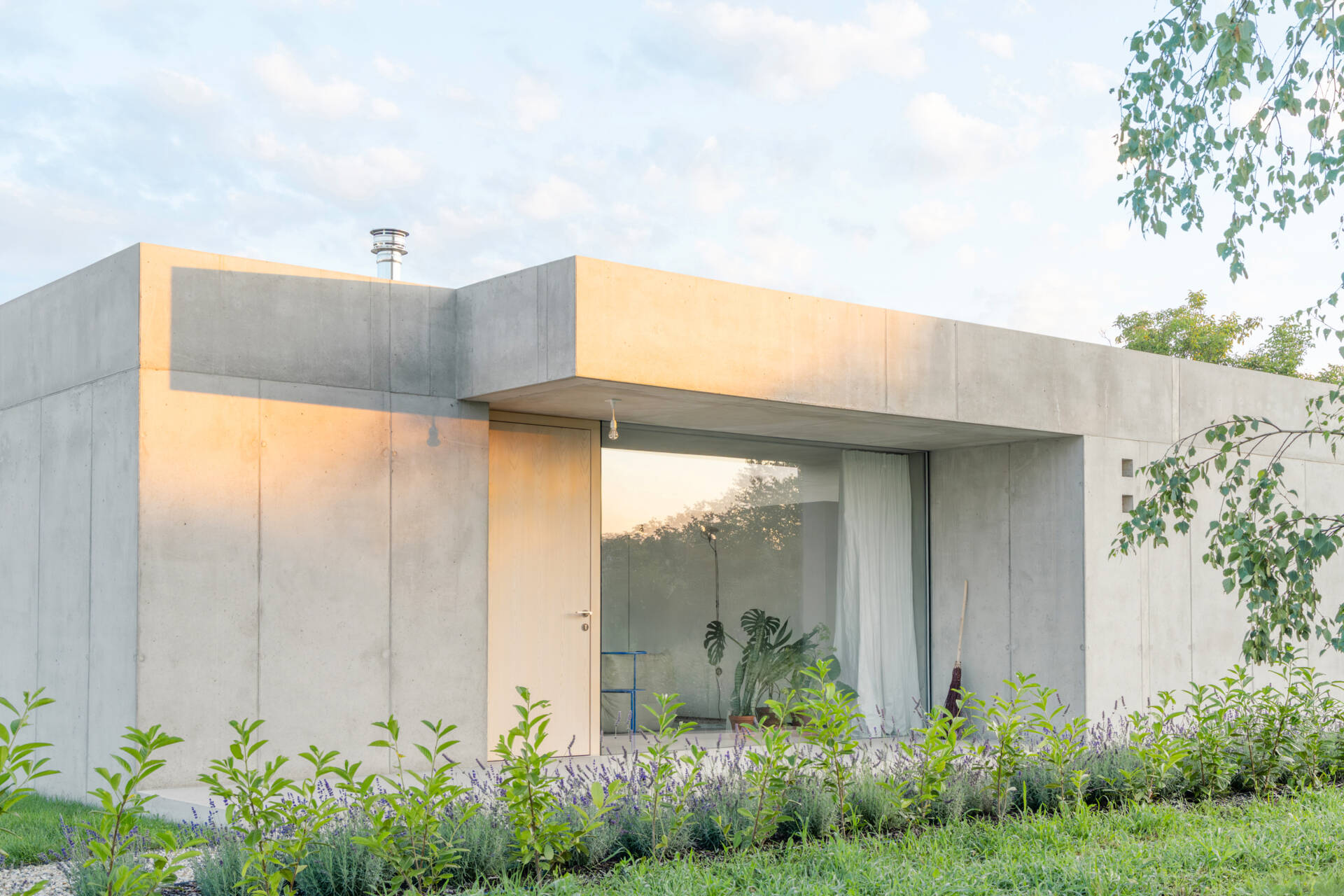 Low and horizontal, this small one bedroom concrete house uses three structural cores and a sliding glass wall to open the entire living space directly to the garden.