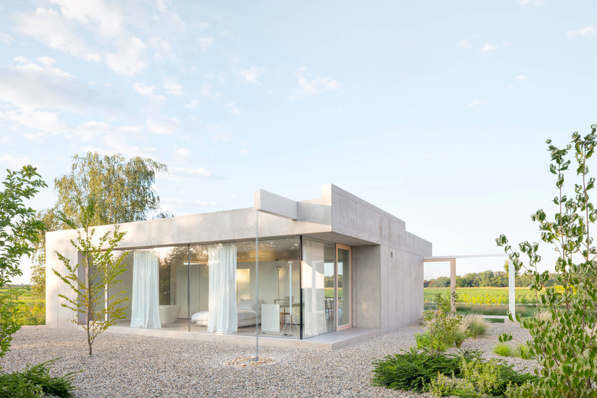 Low and horizontal, this small one bedroom concrete house uses three structural cores and a sliding glass wall to open the entire living space directly to the garden.