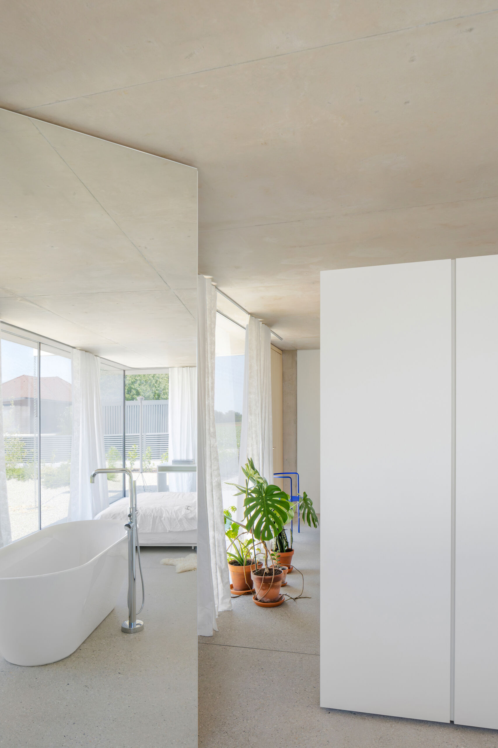 Sleeping and working spaces face a more intimate north east garden. The orientation creates a quieter atmosphere without breaking the openness of the plan. The bathroom is integrated within one of the concrete cores, with mirrored surfaces making the room feel larger.