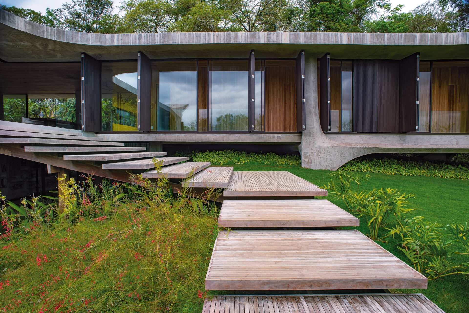An expansive concrete balcony with wood stairs leading to outdoor spaces, extending the home across multiple levels.