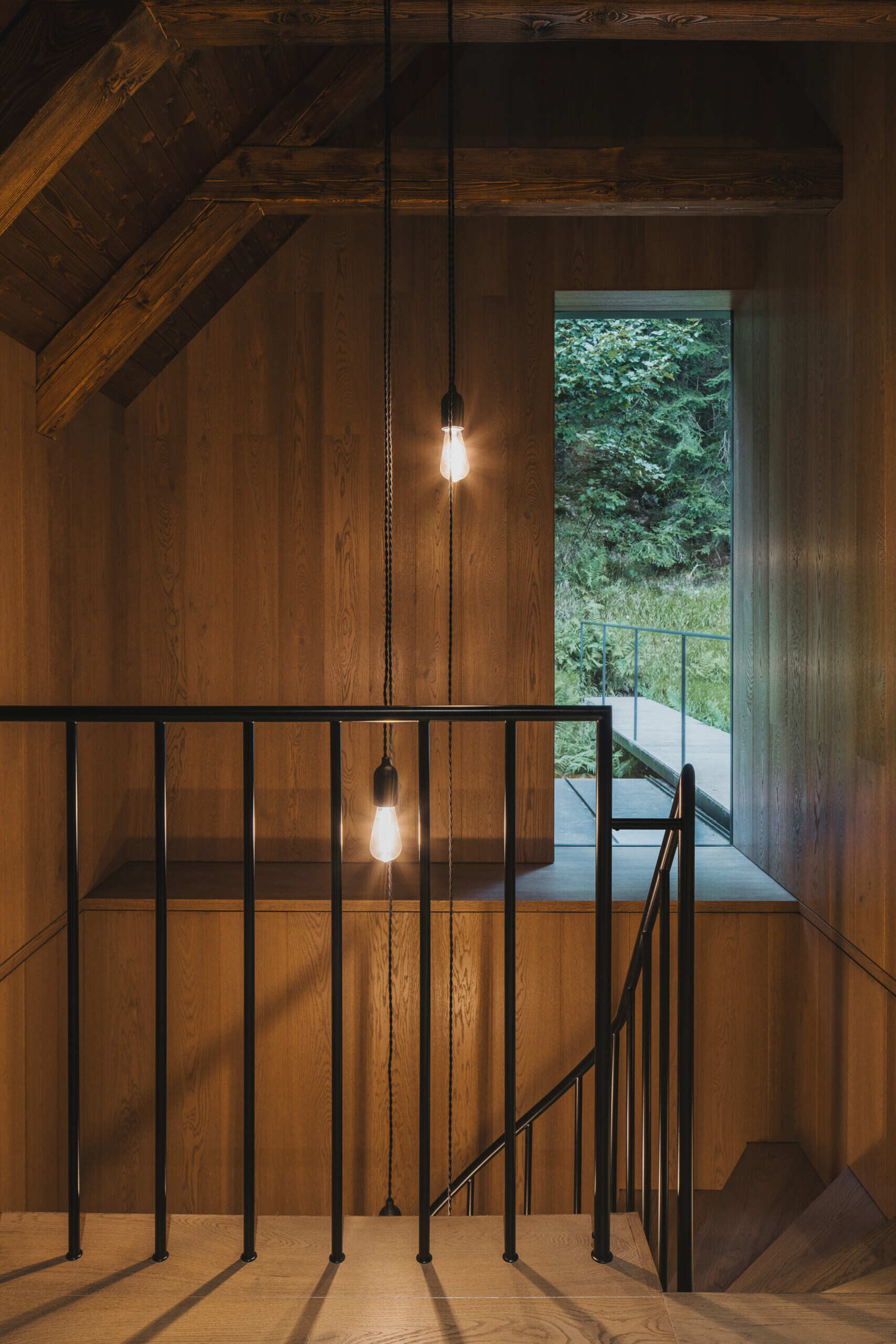 The wood staircase with black metal railing links the ground floor to the attic without disrupting the traditional layout. Its insertion respects the surviving structure while providing clear access to upper-level rooms.
