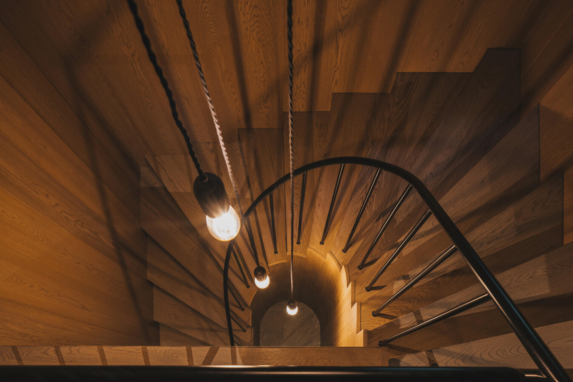 The wood staircase with black metal railing links the ground floor to the attic without disrupting the traditional layout. Its insertion respects the surviving structure while providing clear access to upper-level rooms.