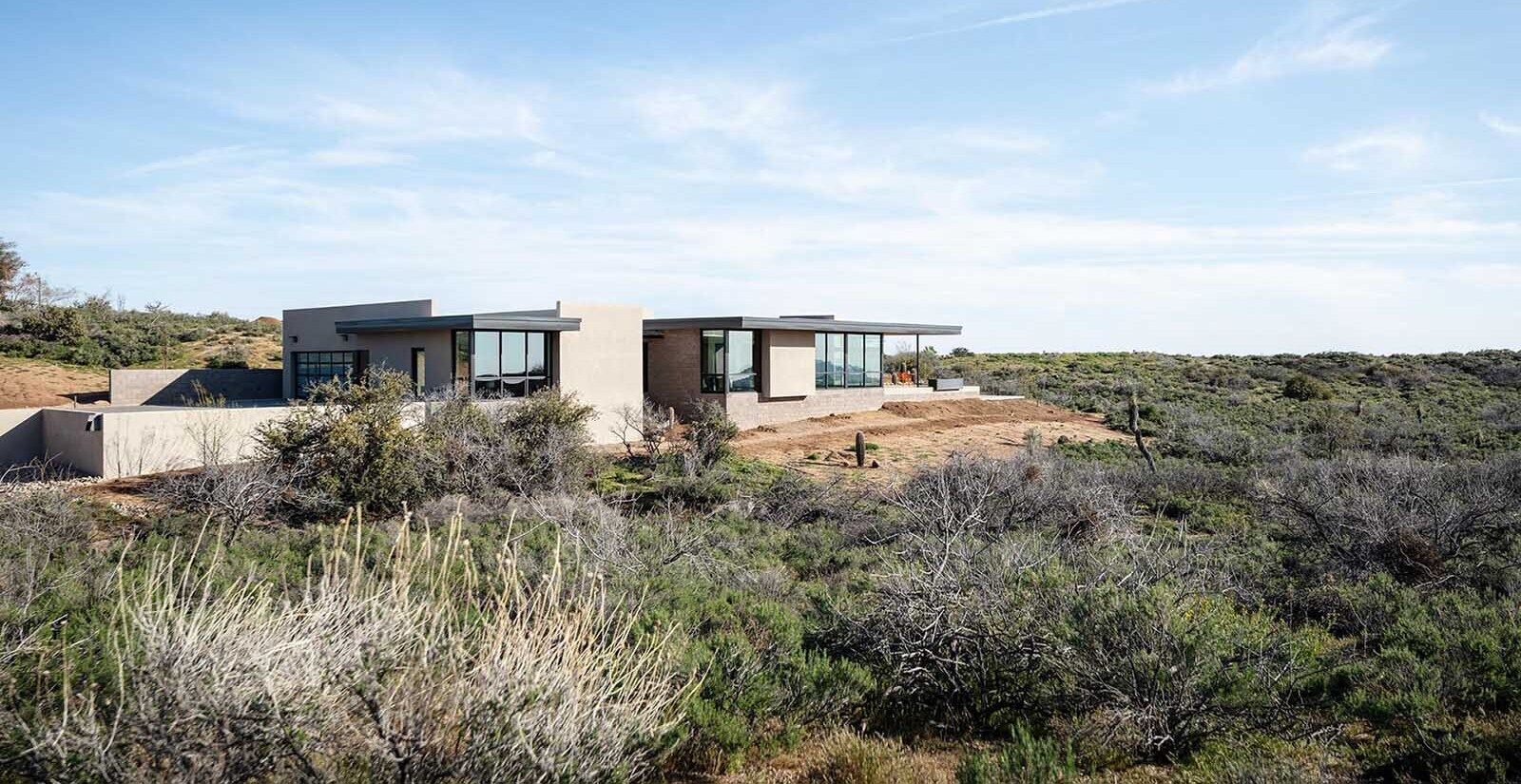 A modern desert home with exposed concrete block, glass, and deep roof overhangs designed for shade.