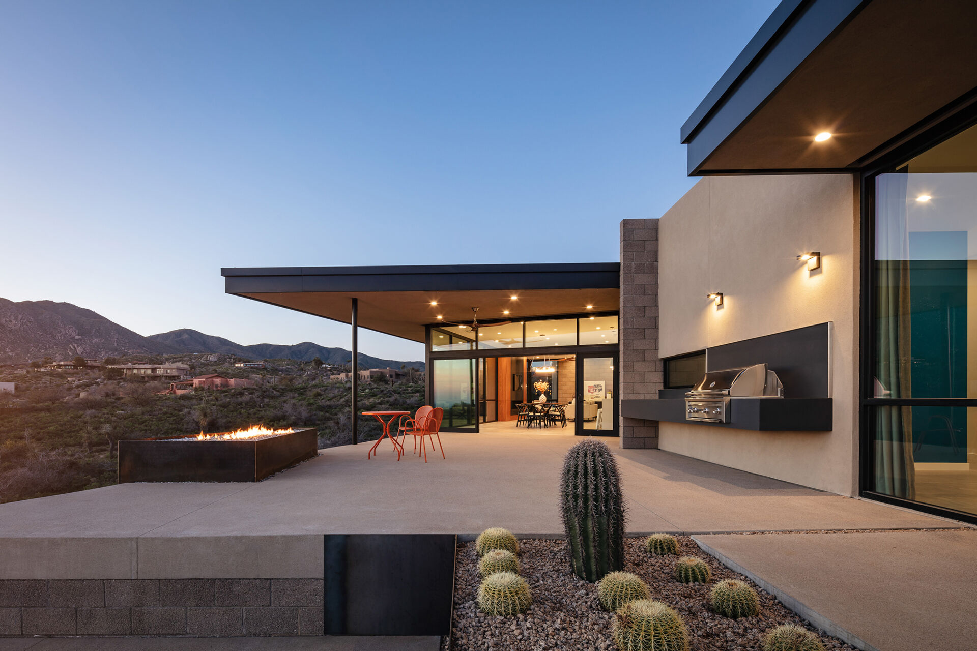 A terraced desert patio with raw steel planters, cacti, and a clean concrete finish.