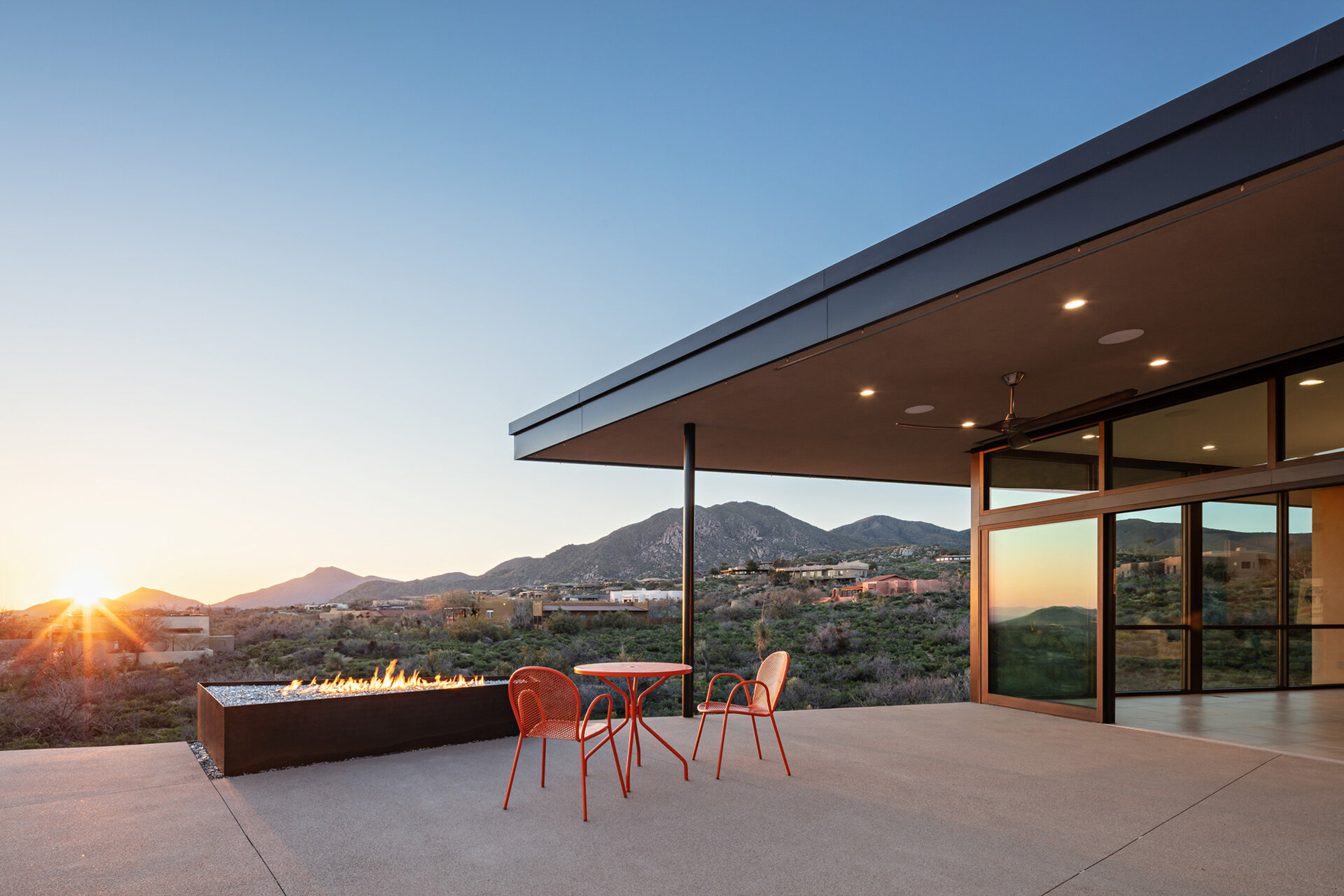A terraced desert patio with raw steel planters, cacti, and a clean concrete finish.