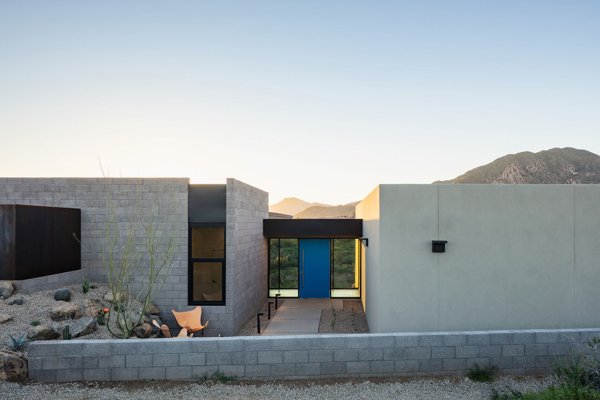A glass bridge entry with a bold blue door and a floating wood ceiling that extends into a feature wall.