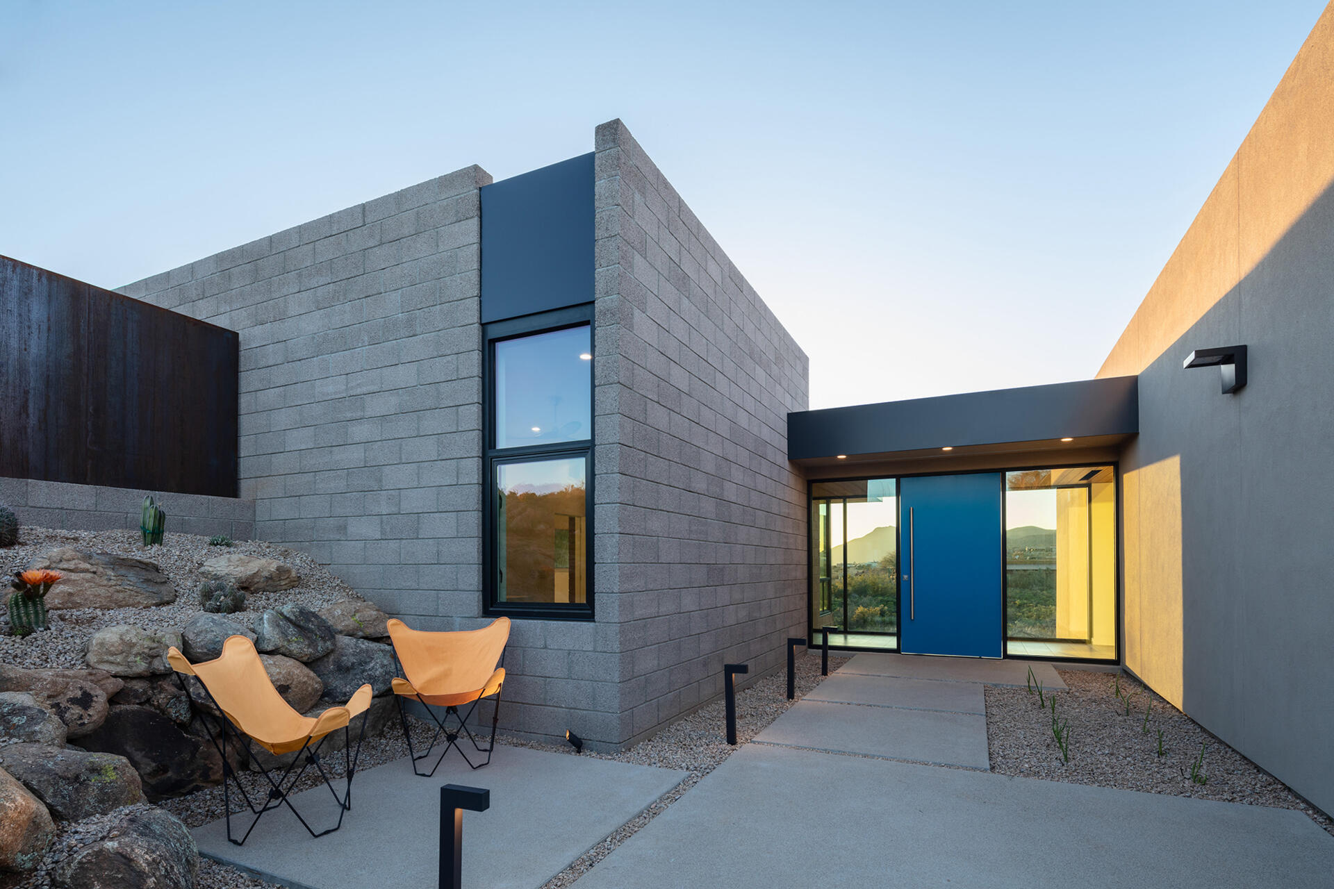 A glass bridge entry with a bold blue door and a floating wood ceiling that extends into a feature wall.