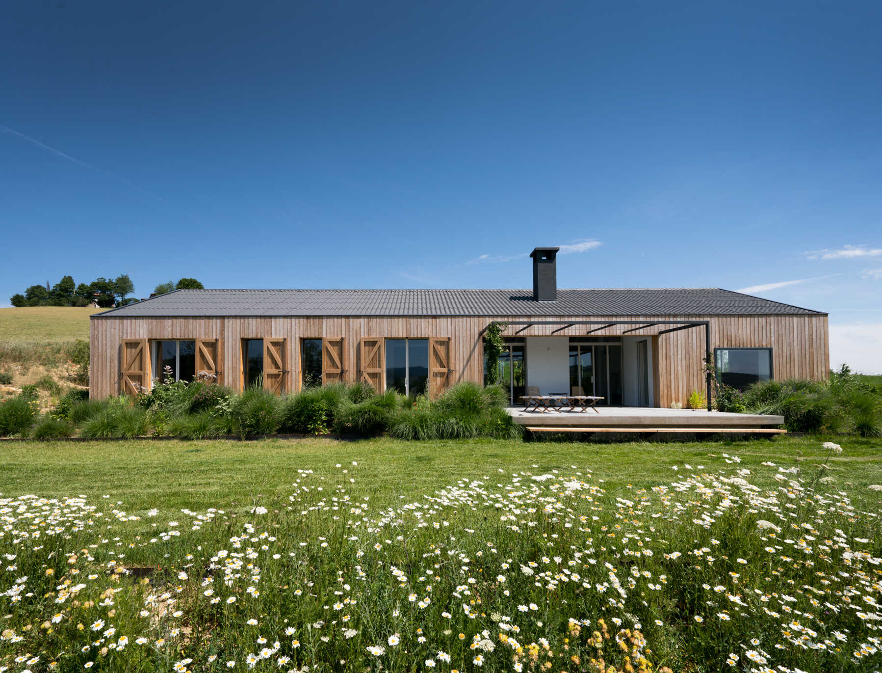 The farmhouse’s larch wood siding ages to a soft gray, offering natural insulation and blending seamlessly into the Italian countryside.