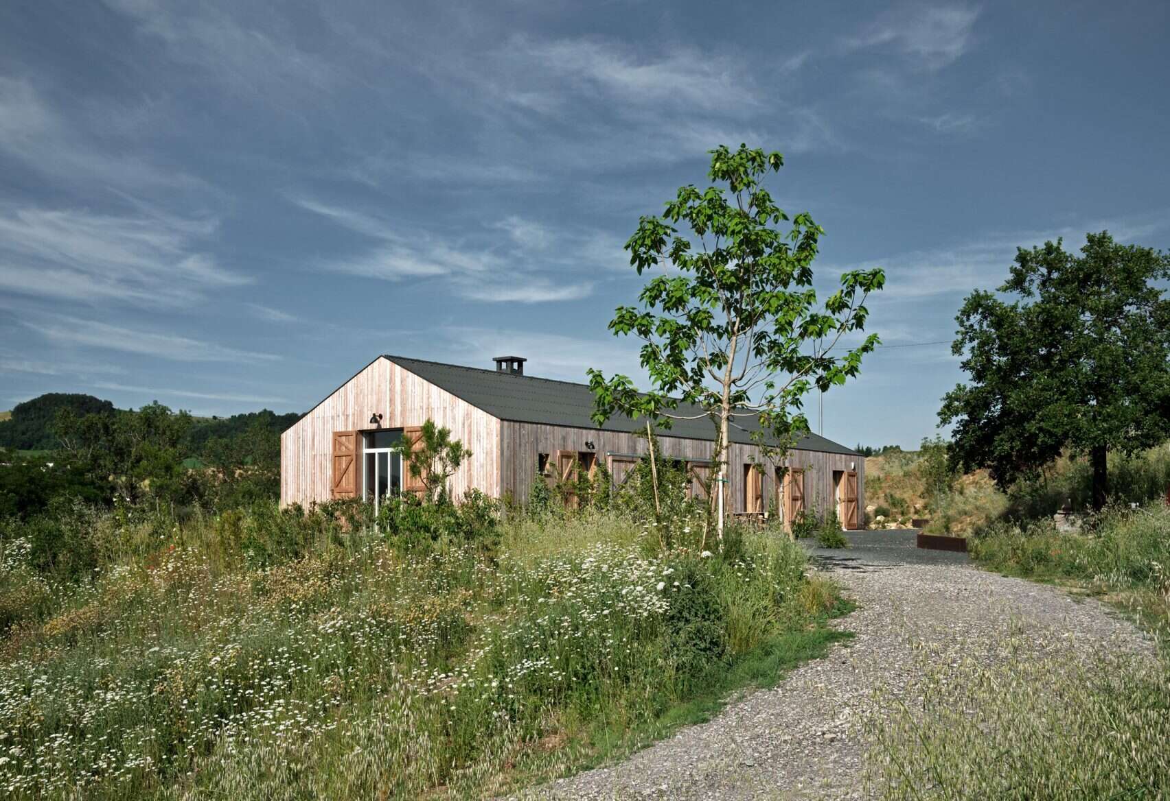 The farmhouse’s larch wood siding ages to a soft gray, offering natural insulation and blending seamlessly into the Italian countryside.
