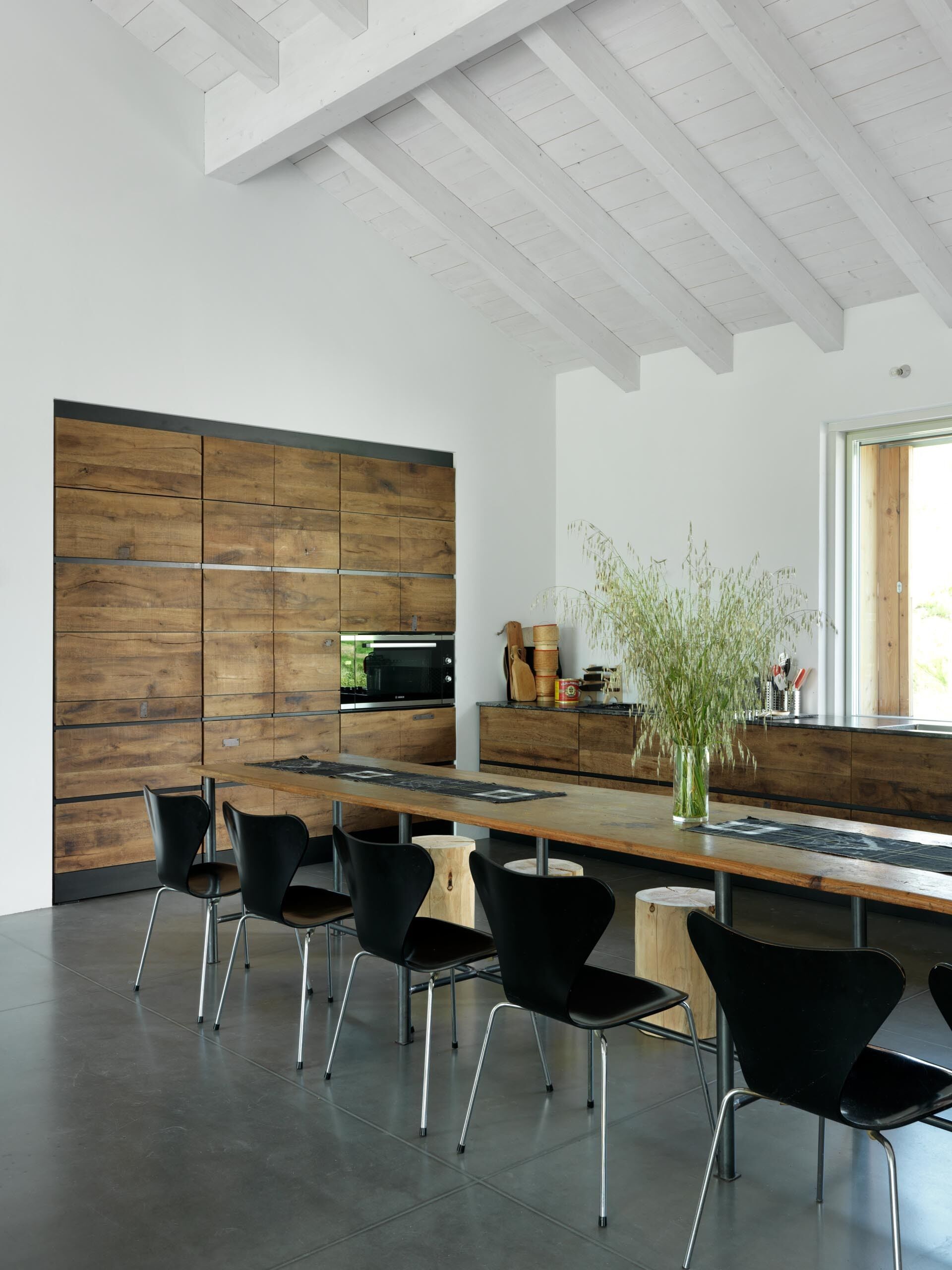 The custom kitchen uses reclaimed wood, enhancing the farmhouse aesthetic without detracting from the minimalist interior.