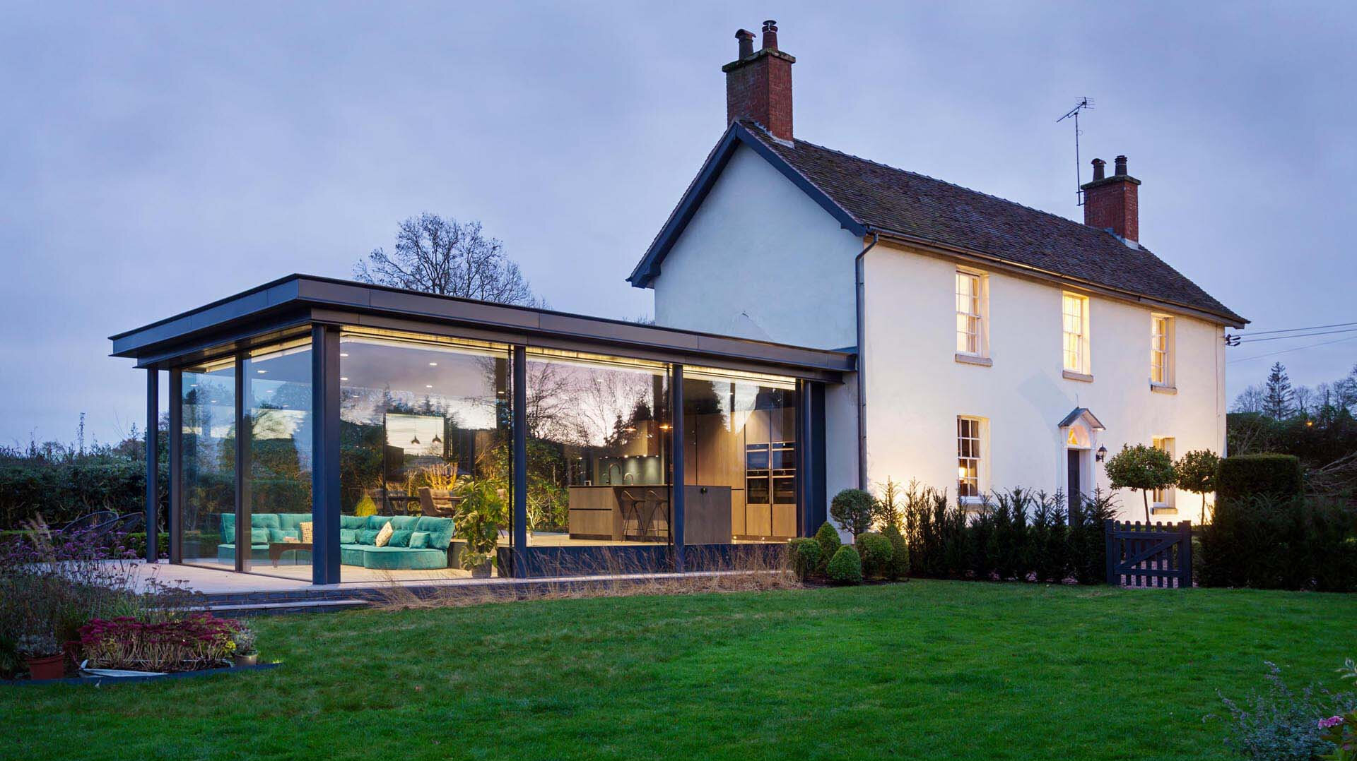 A modern glass extension adds a fresh layer to this historic English cottage, blending old charm with contemporary design.
