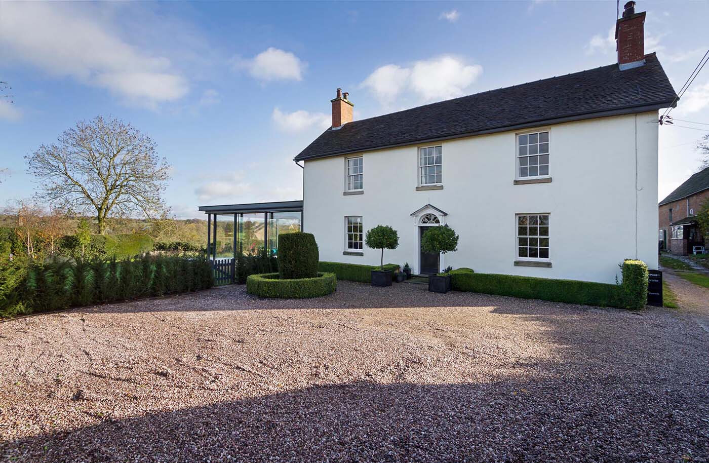 A modern glass extension adds a fresh layer to this historic English cottage, blending old charm with contemporary design.