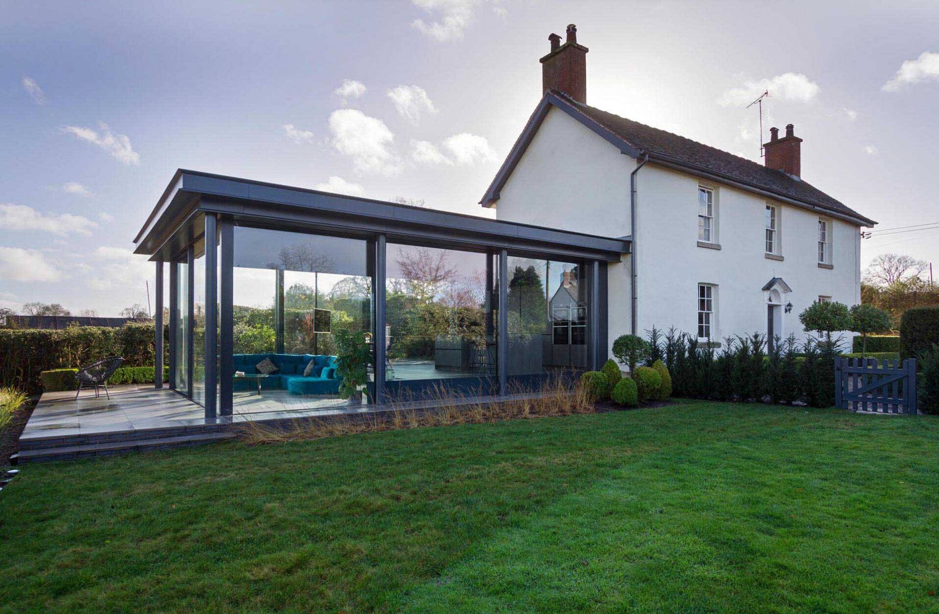 A modern glass extension adds a fresh layer to this historic English cottage, blending old charm with contemporary design.