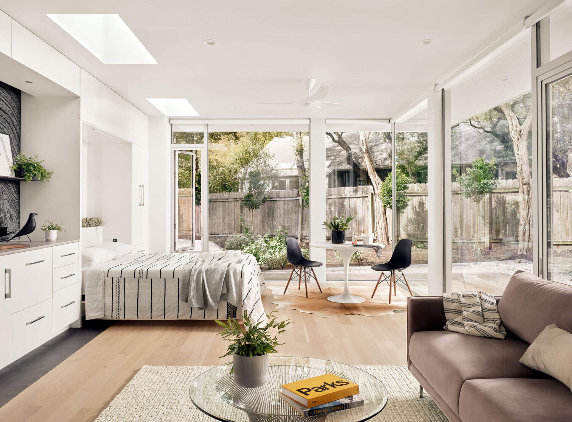 A dining nook and living area share space in this Austin guest house, where a Murphy bed folds down from custom cabinetry to transform the room into a sleeping area.