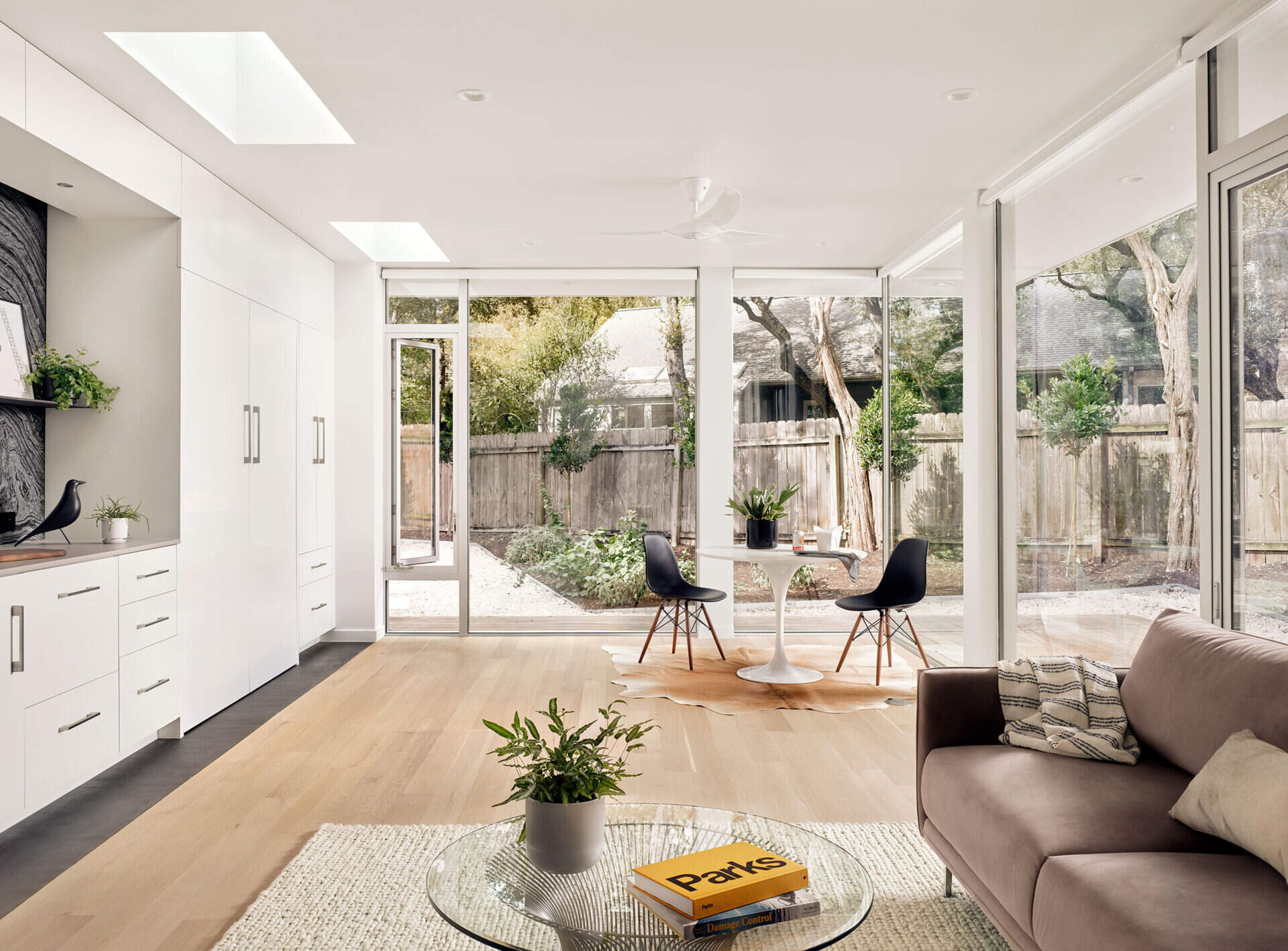 A dining nook and living area share space in this Austin guest house, where a Murphy bed folds down from custom cabinetry to transform the room into a sleeping area.