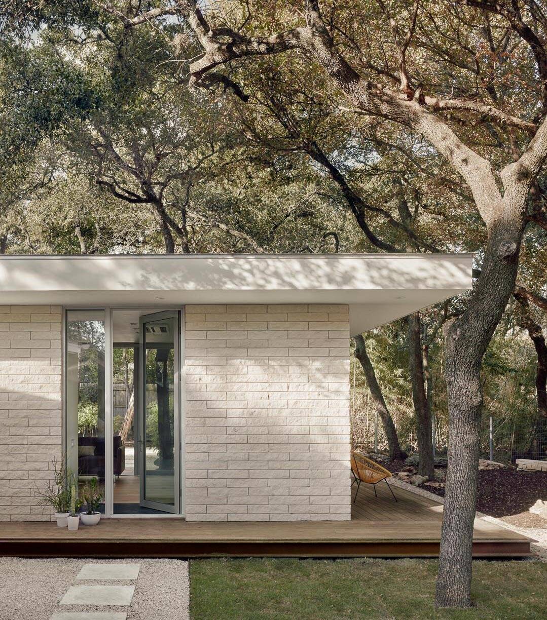 An ipe wood deck surrounds this small Austin guest house, while floor-to-ceiling glass and a simple glass entry help the 540 square foot home feel open and bright.