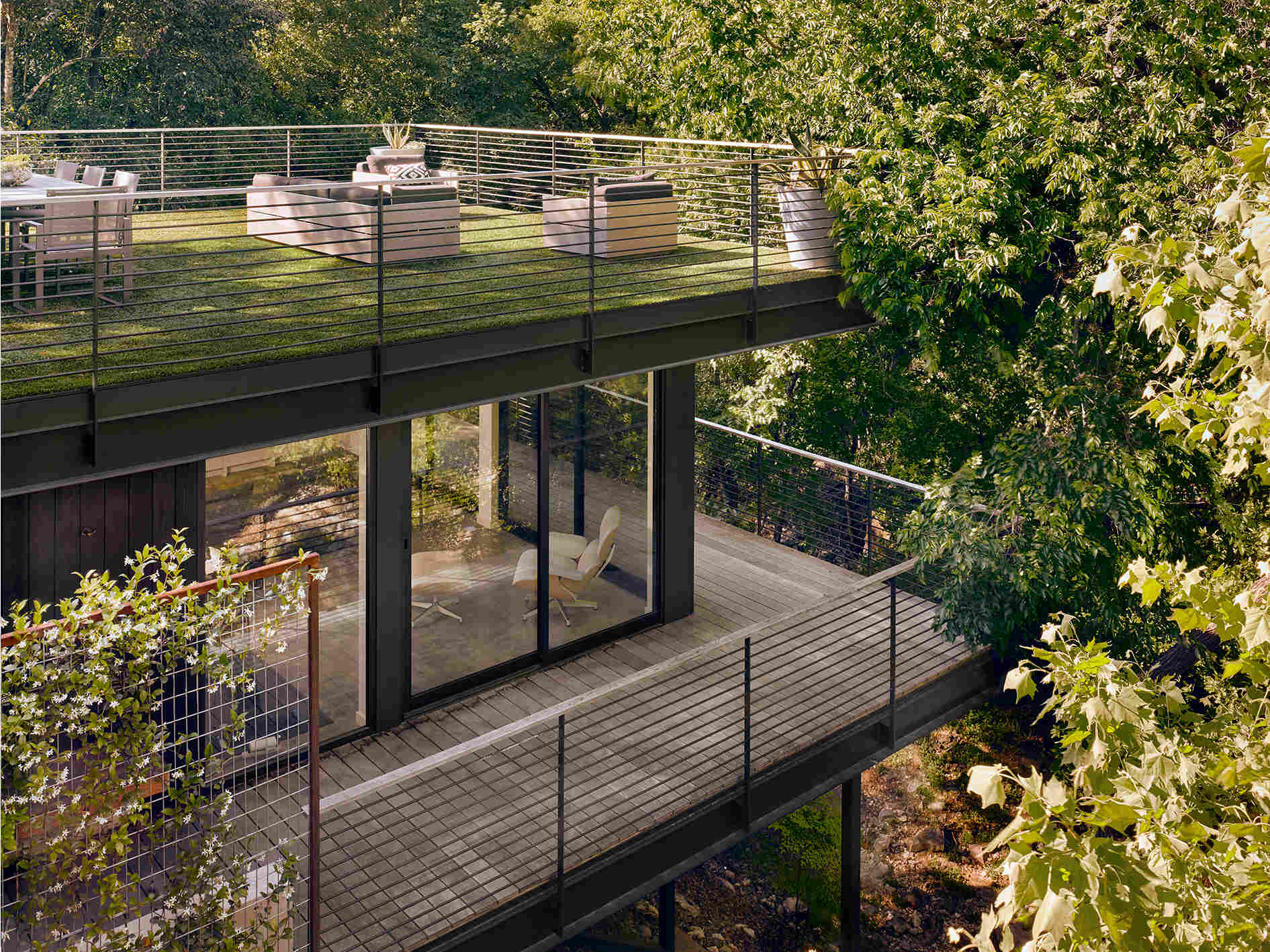 Built into a steep site, this addition sits below the home and opens toward a creek, shaping a unique way to experience the landscape.