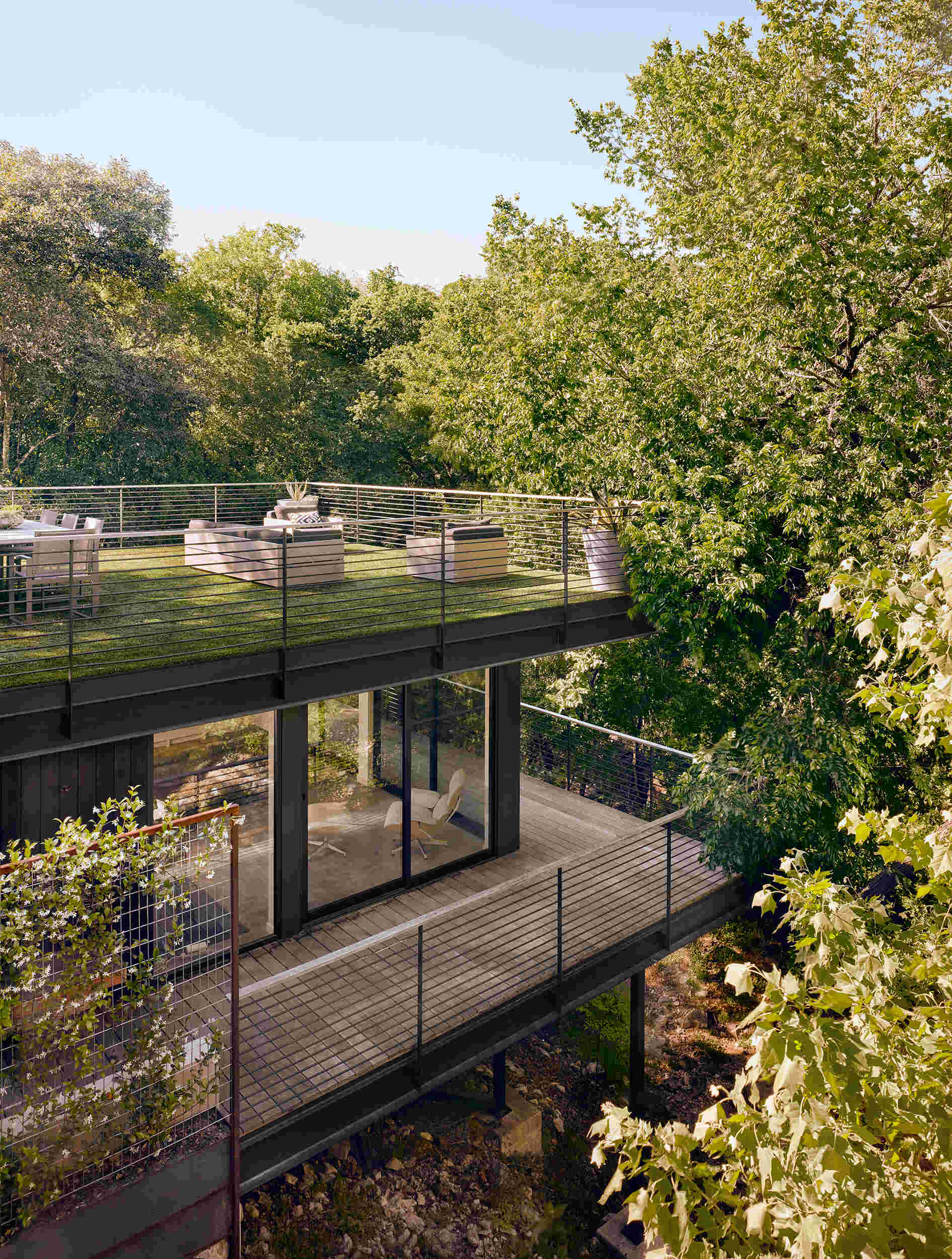 El techo verde se extiende hasta la terraza que rodea la casa, brindando vistas elevadas y fácil acceso a toda la casa.