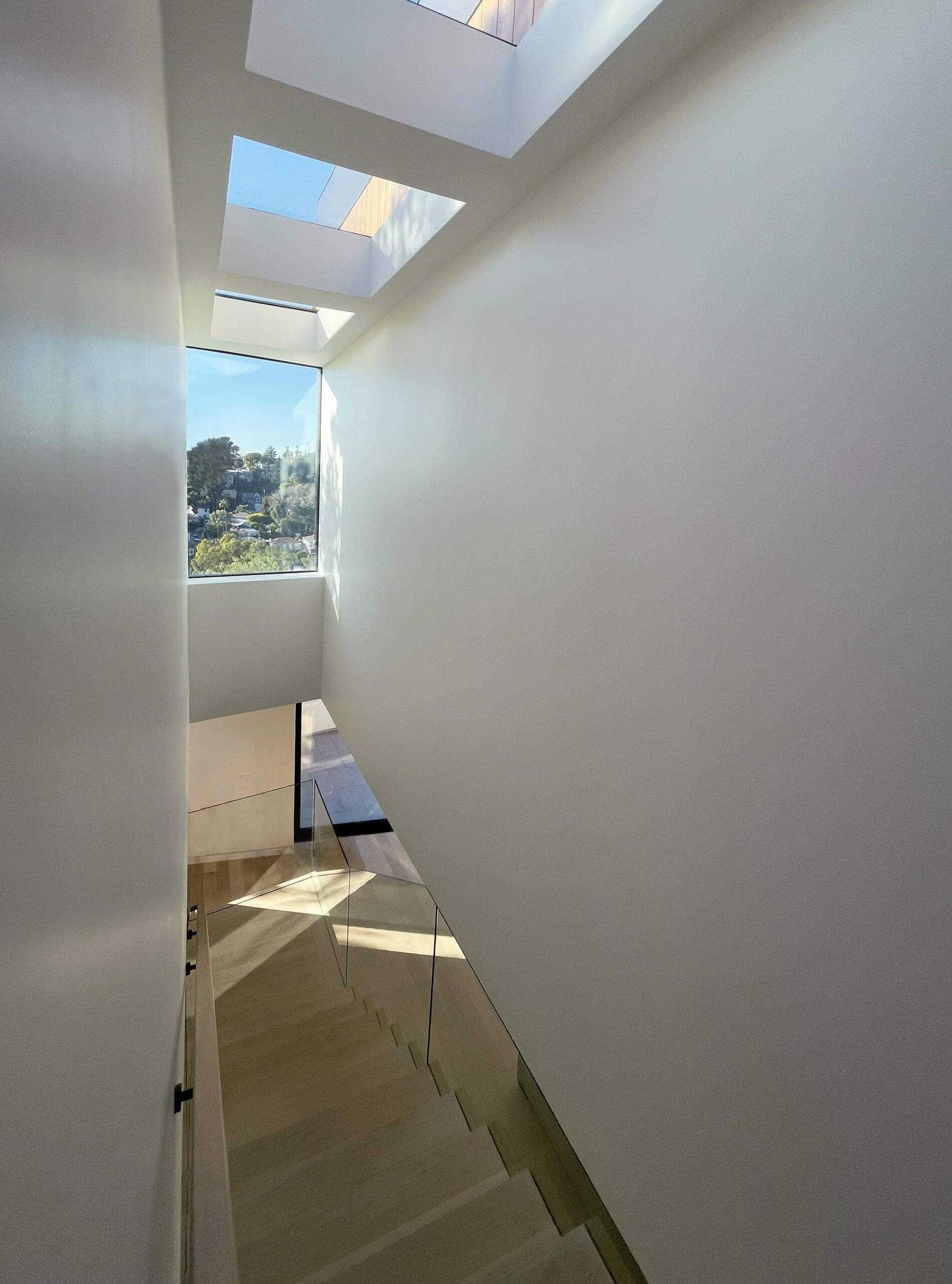 The long series of skylights filters light intro the staircase, cuts through the center of the home, creating a clear line from front to back. This “slot” pulls daylight deep inside and links the different spaces in a subtle way.
